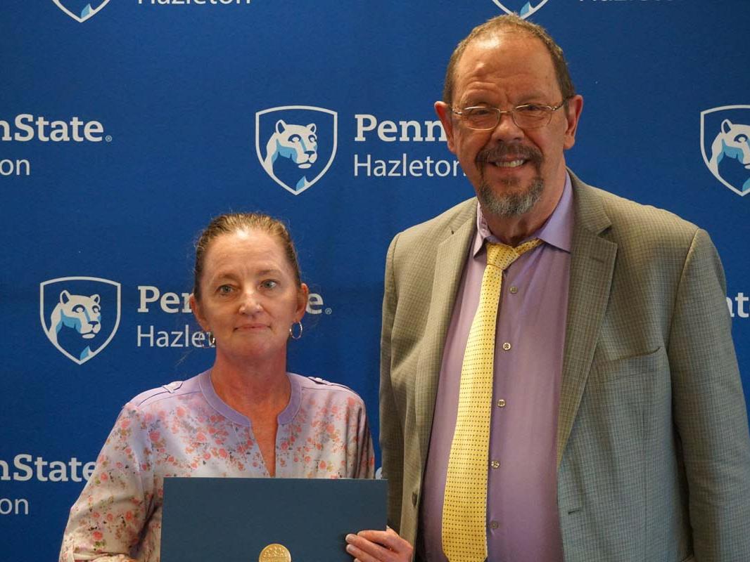 Woman holding certificate and standing next to man in suit.