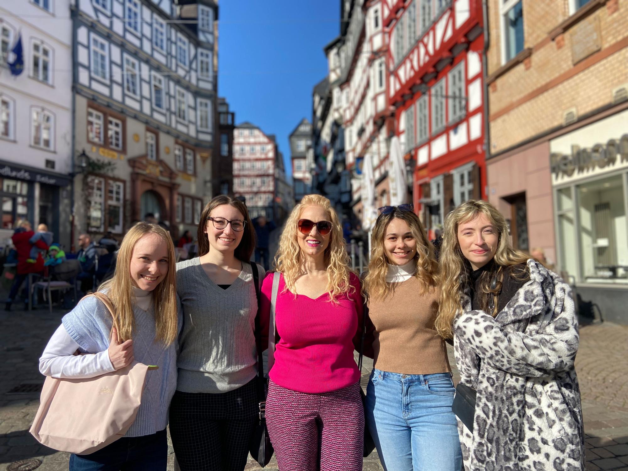 A group of students and instructors pose on cobblestone street in historical German town.