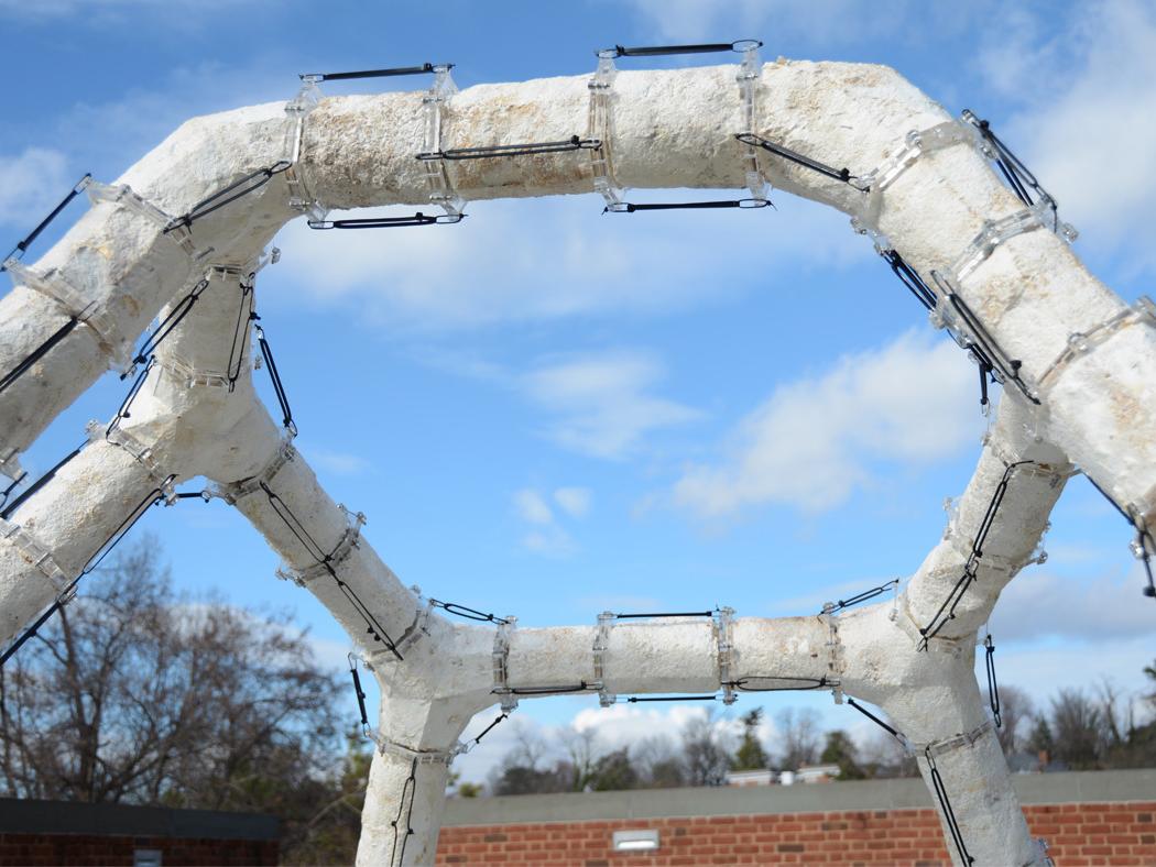 A view of a white architectural structure looking up through the middle at a blue and white sky