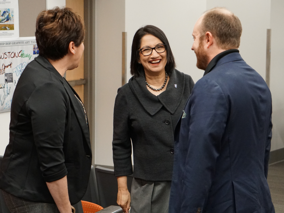 Woman laughing and smiling while standing beside a man and woman.