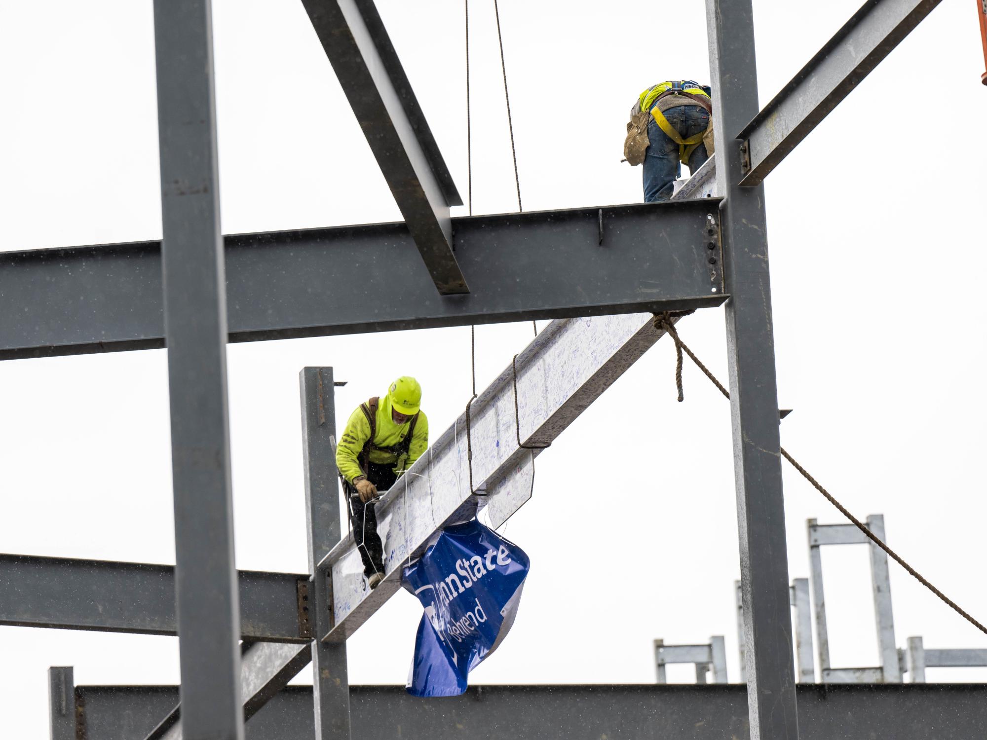 Steelworkers set a beam into place at the site of Penn State Behrend's new Erie Hall.
