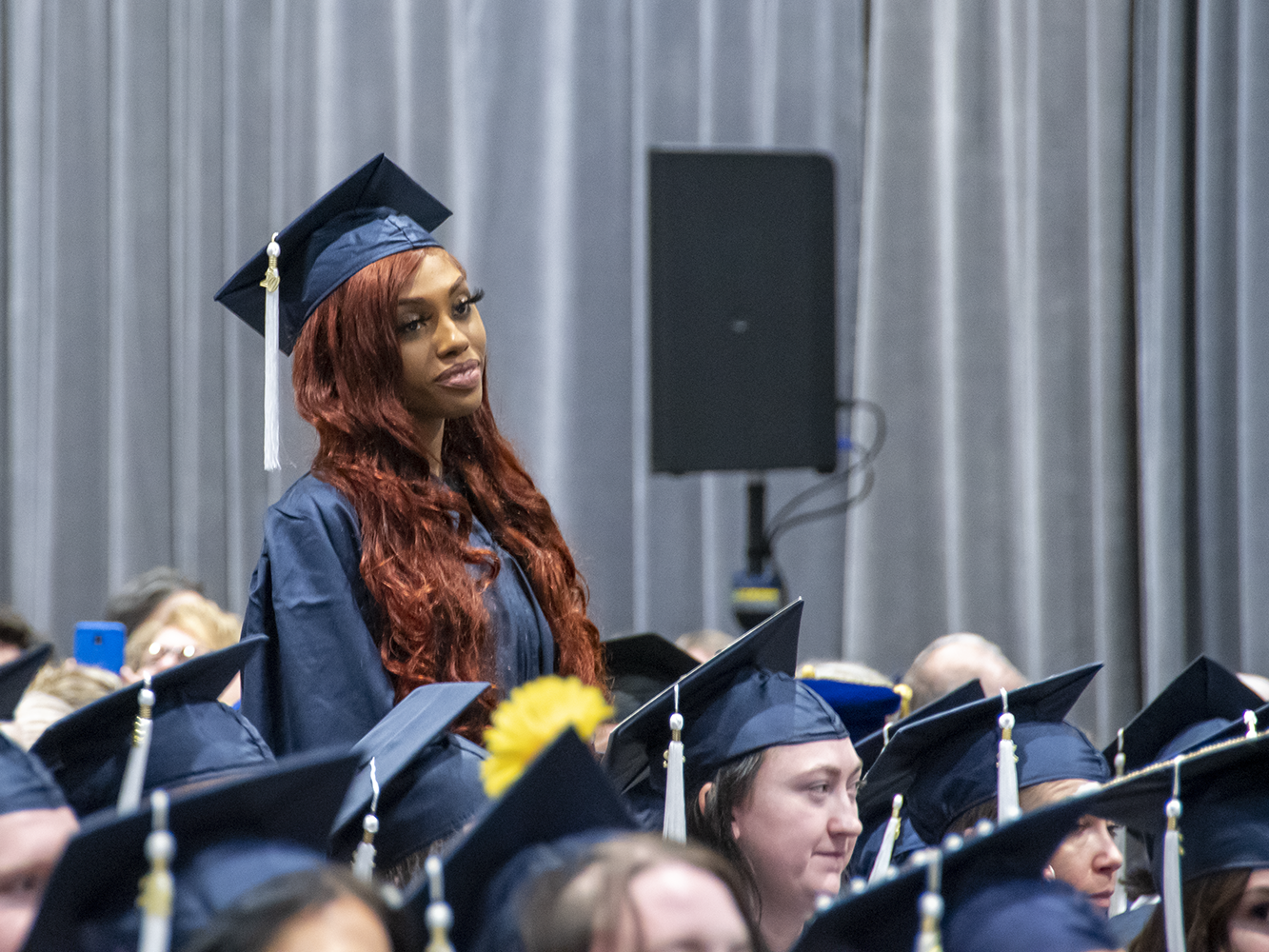 A student stands during commencement.