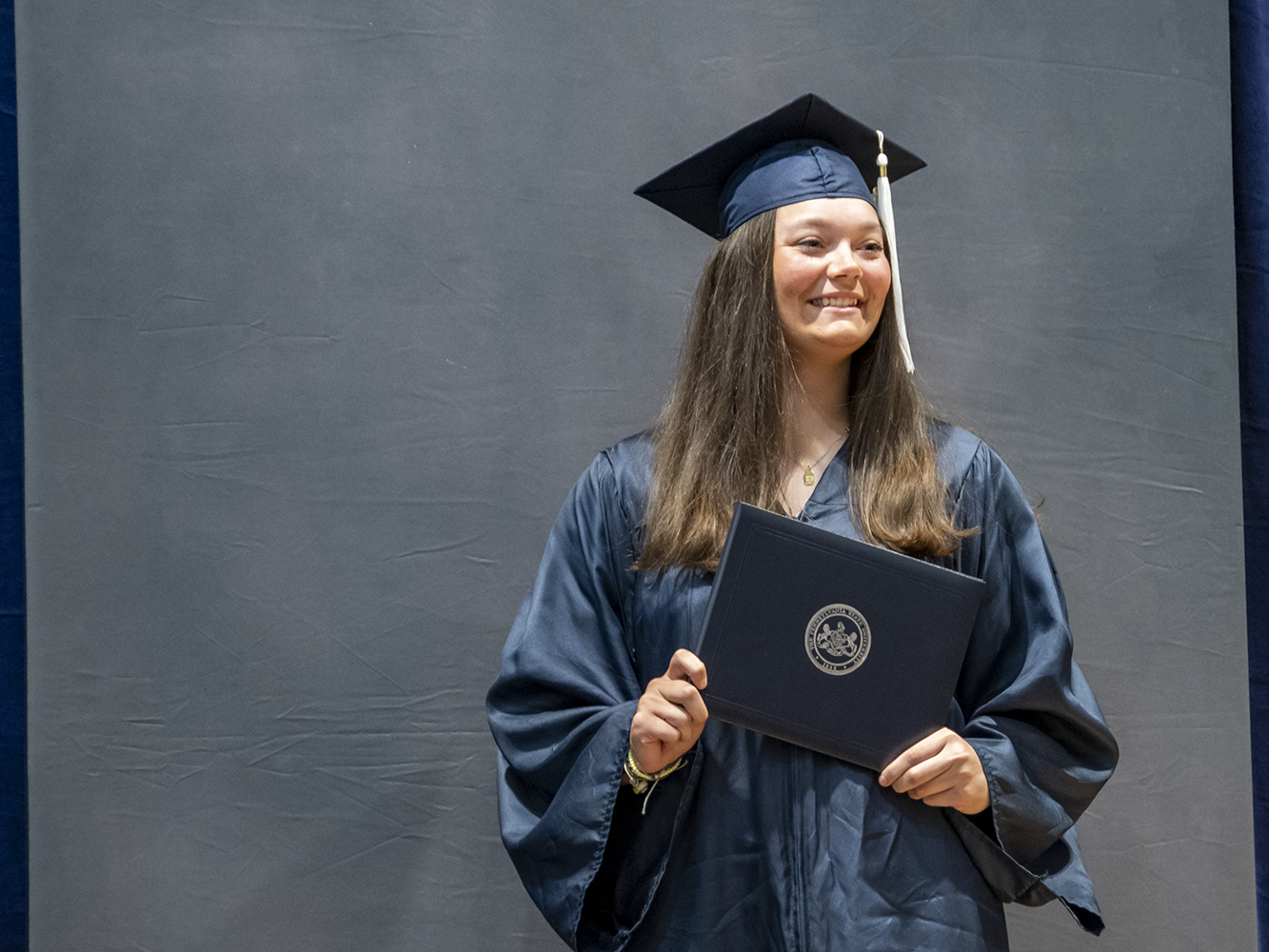 A female graduate poses with diploma.