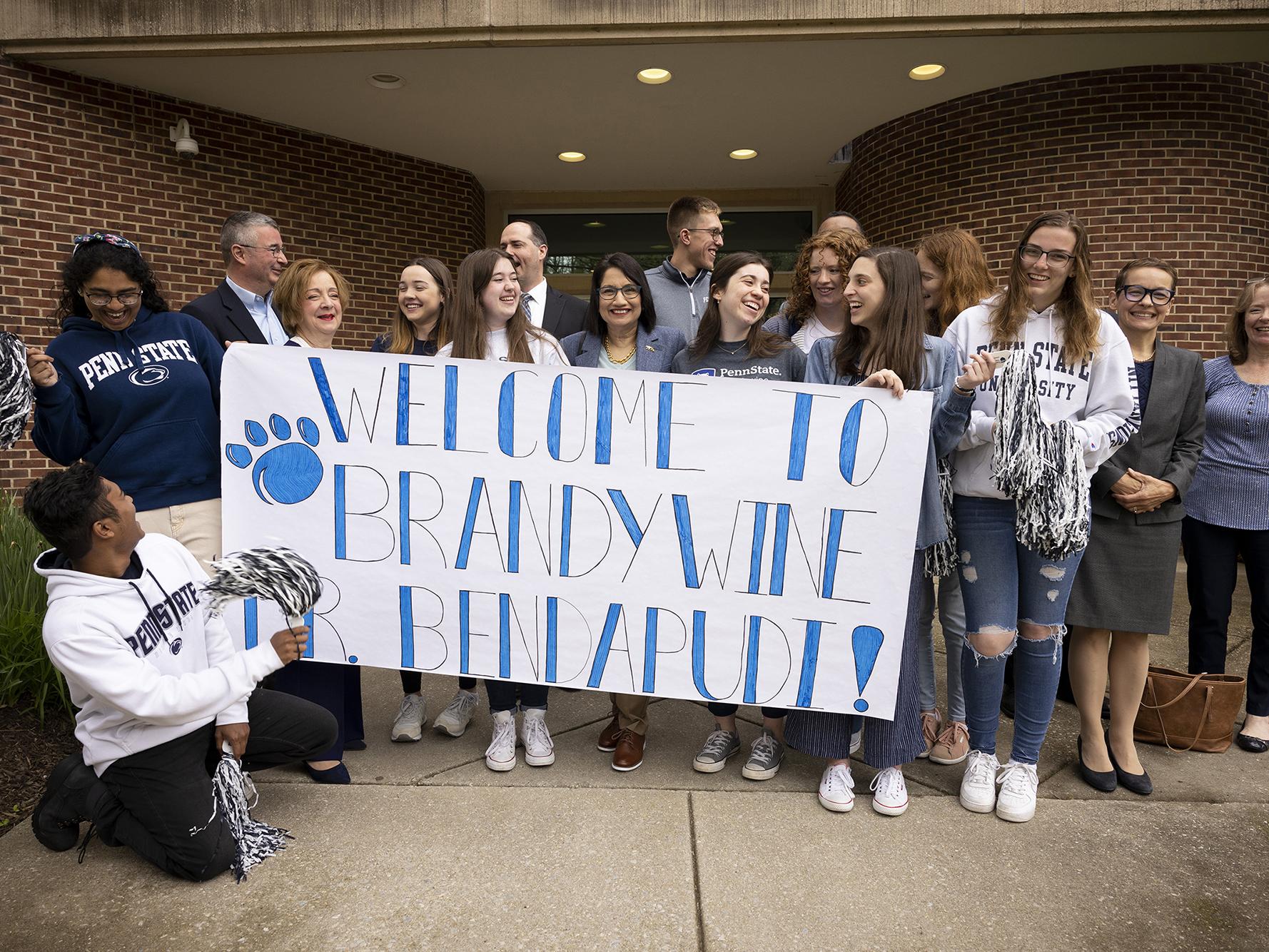 A group of 15 people stands behind a banner.