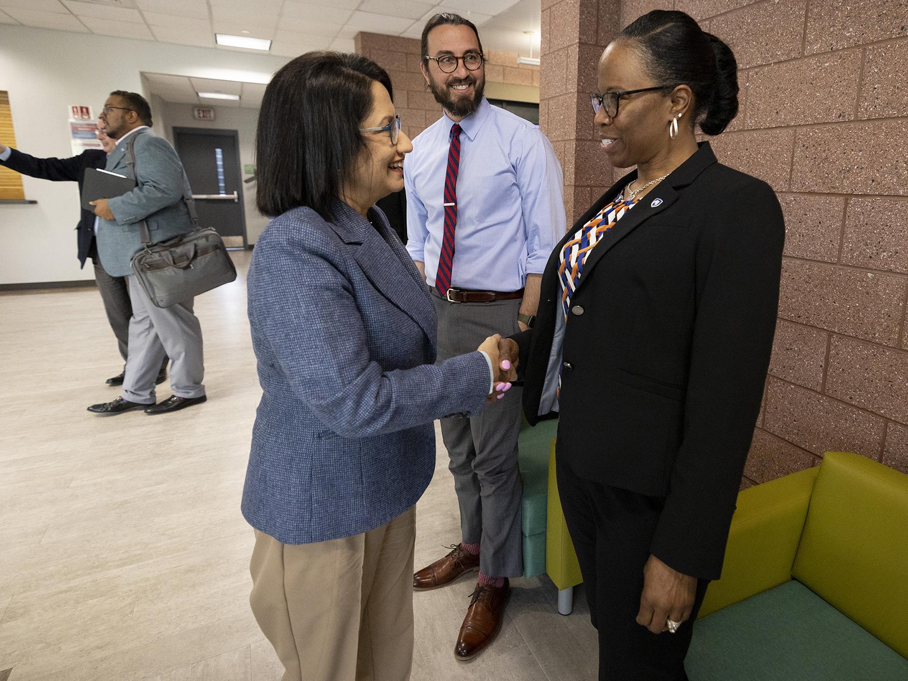 Two women shake hands.