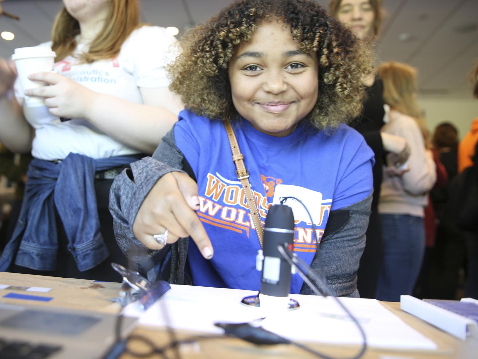 A girl points to a microscope slide.