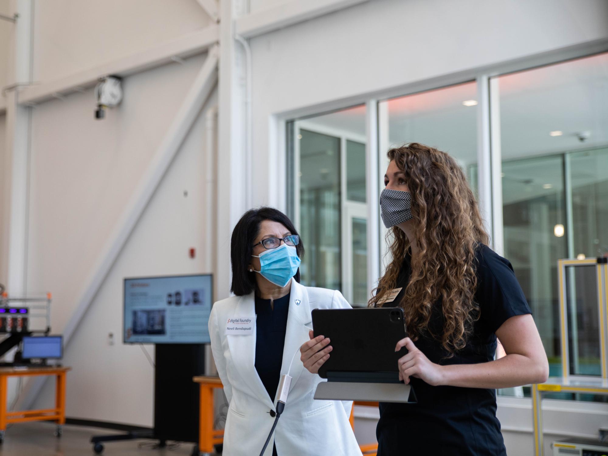 A student holds an iPad while talking with University president