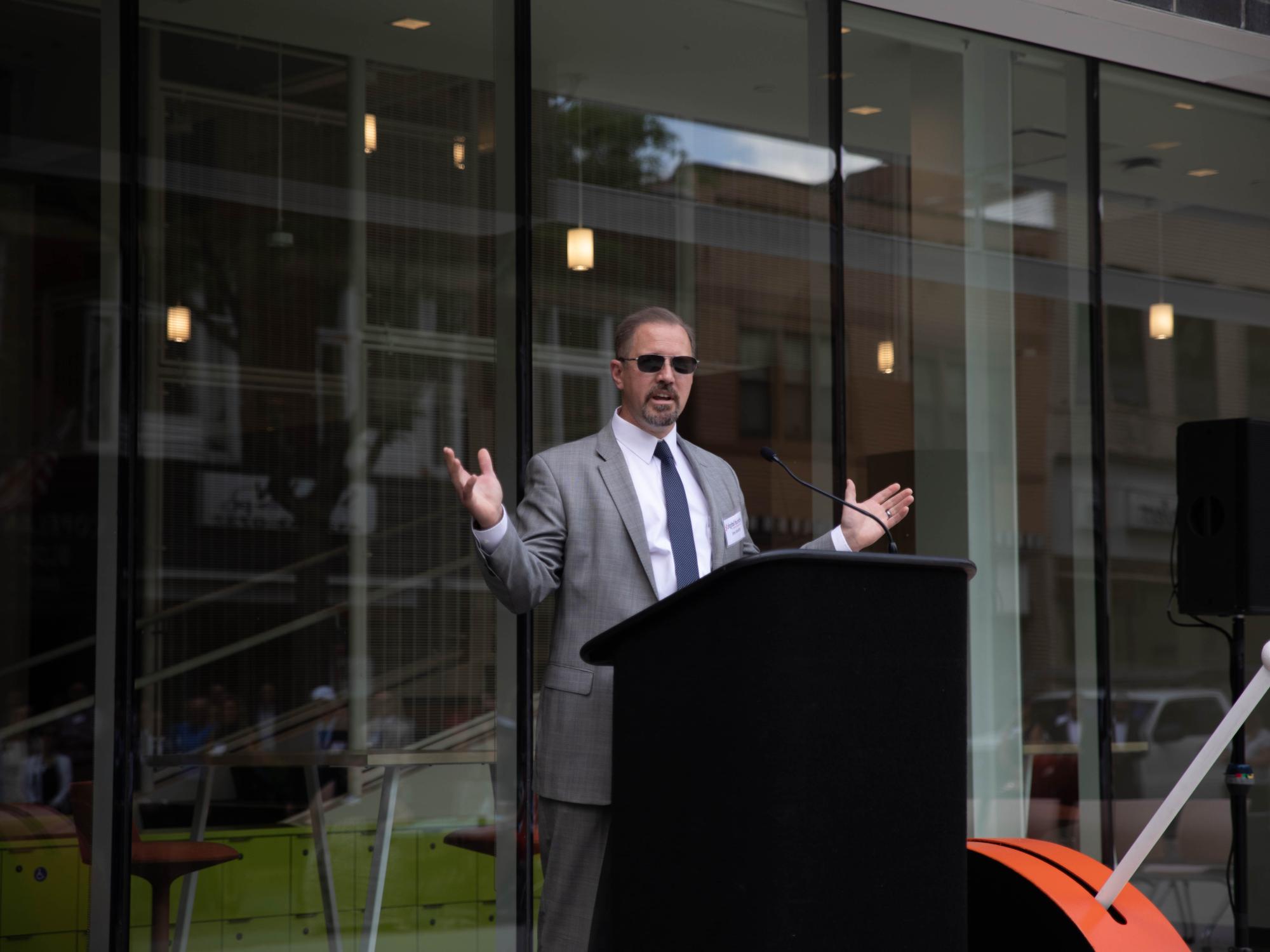 Man stands at podium with outstretched arms