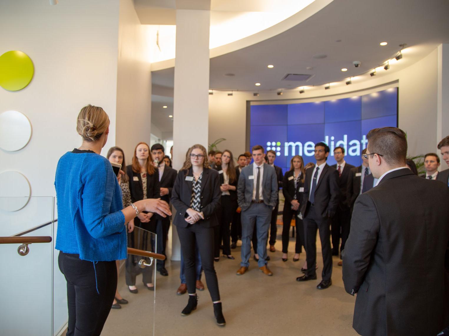 students in professional attire look at woman presenting