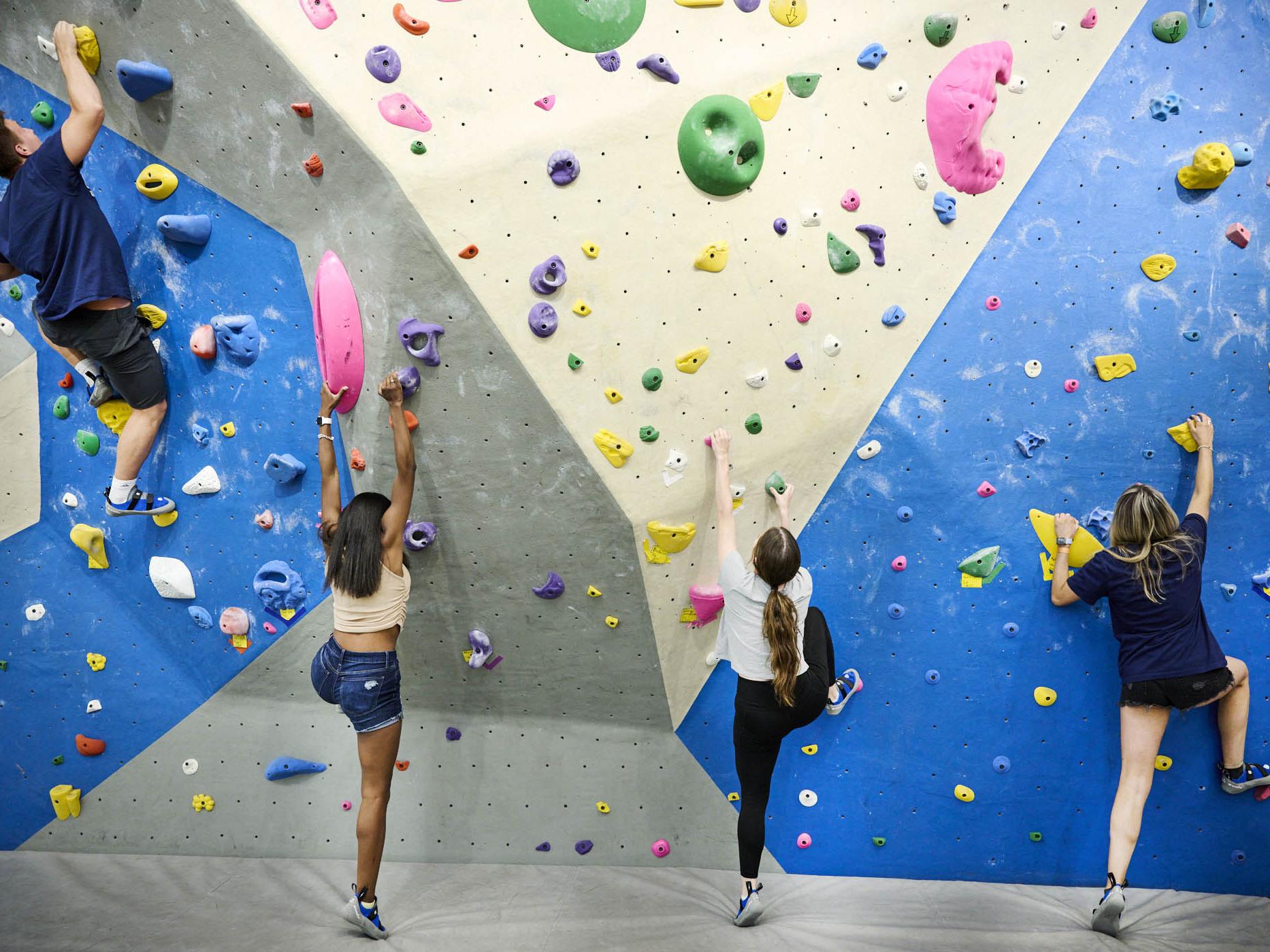 Four students climbing a rock wall in the IM Buidling