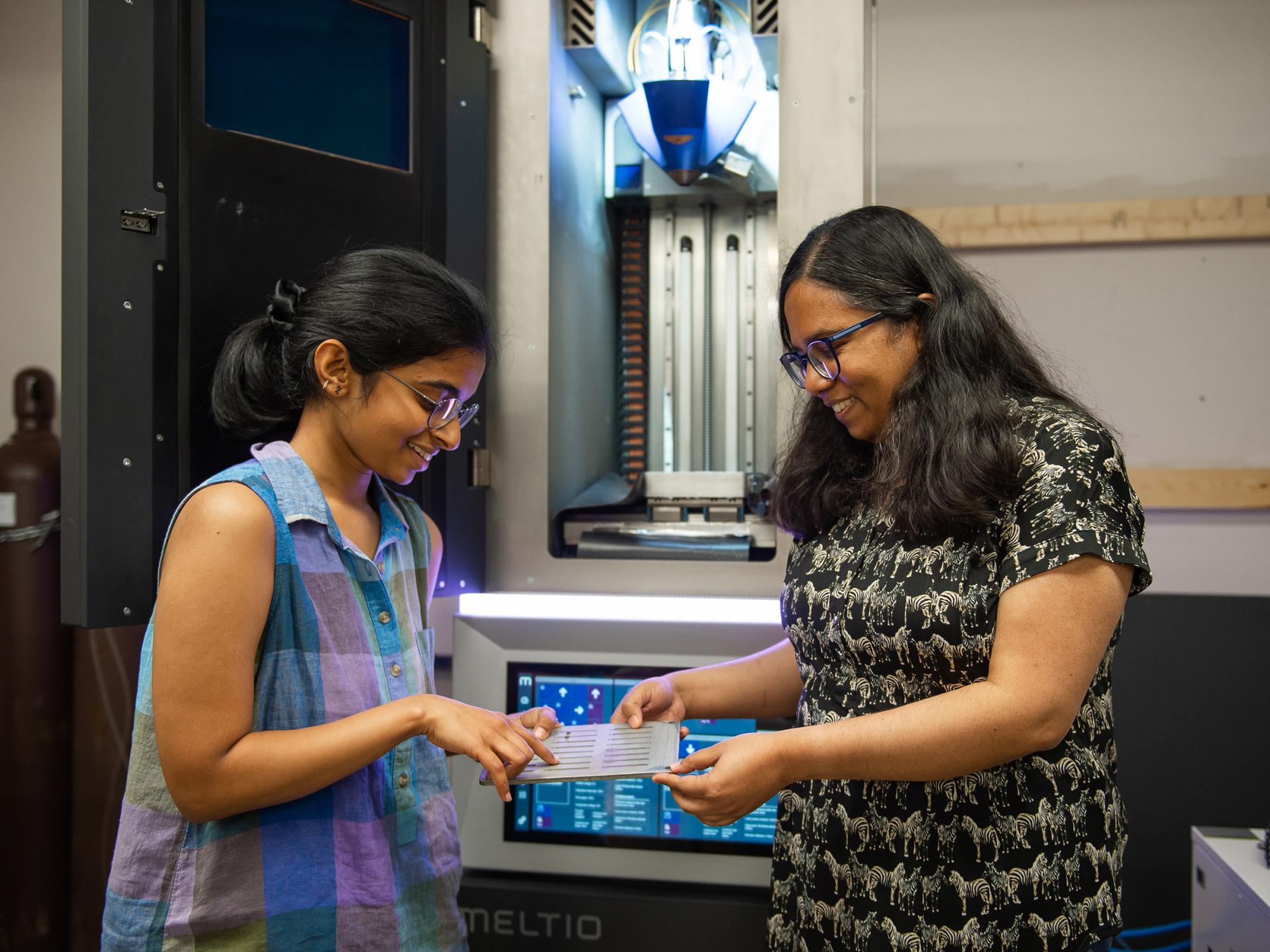 two women examine equipment in research lab