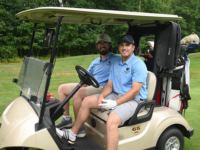 Two student-athletes on a golf cart.