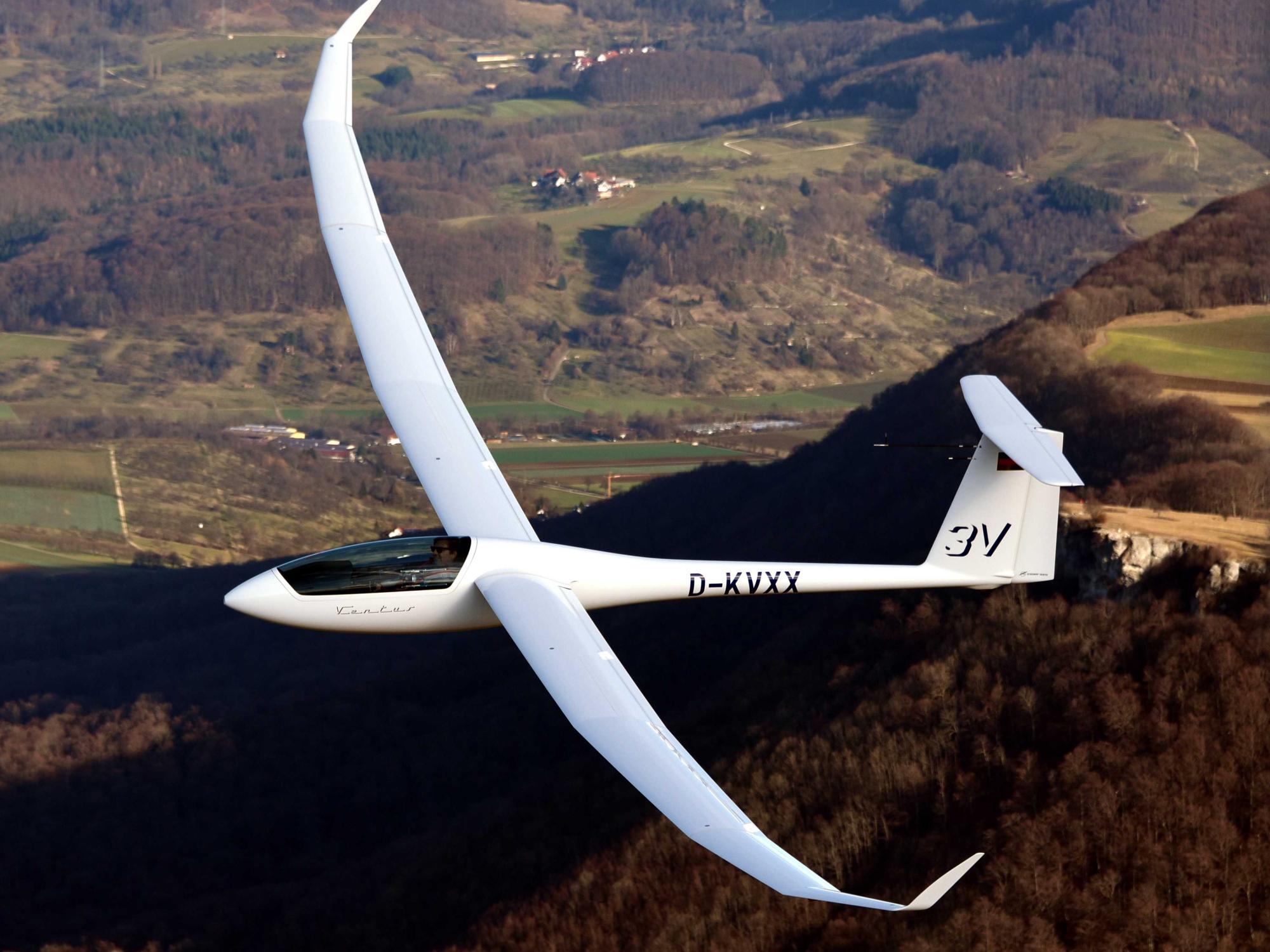A sailplane above rolling green hills