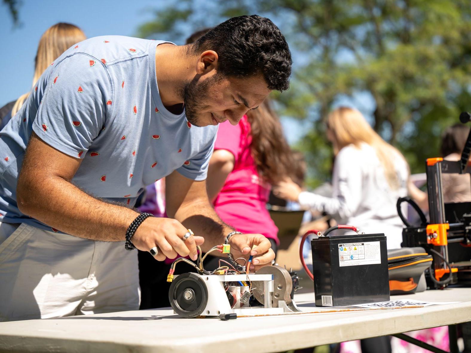 A student works on an electrical device on a table at the Discovery Fair at Penn State Behrend.