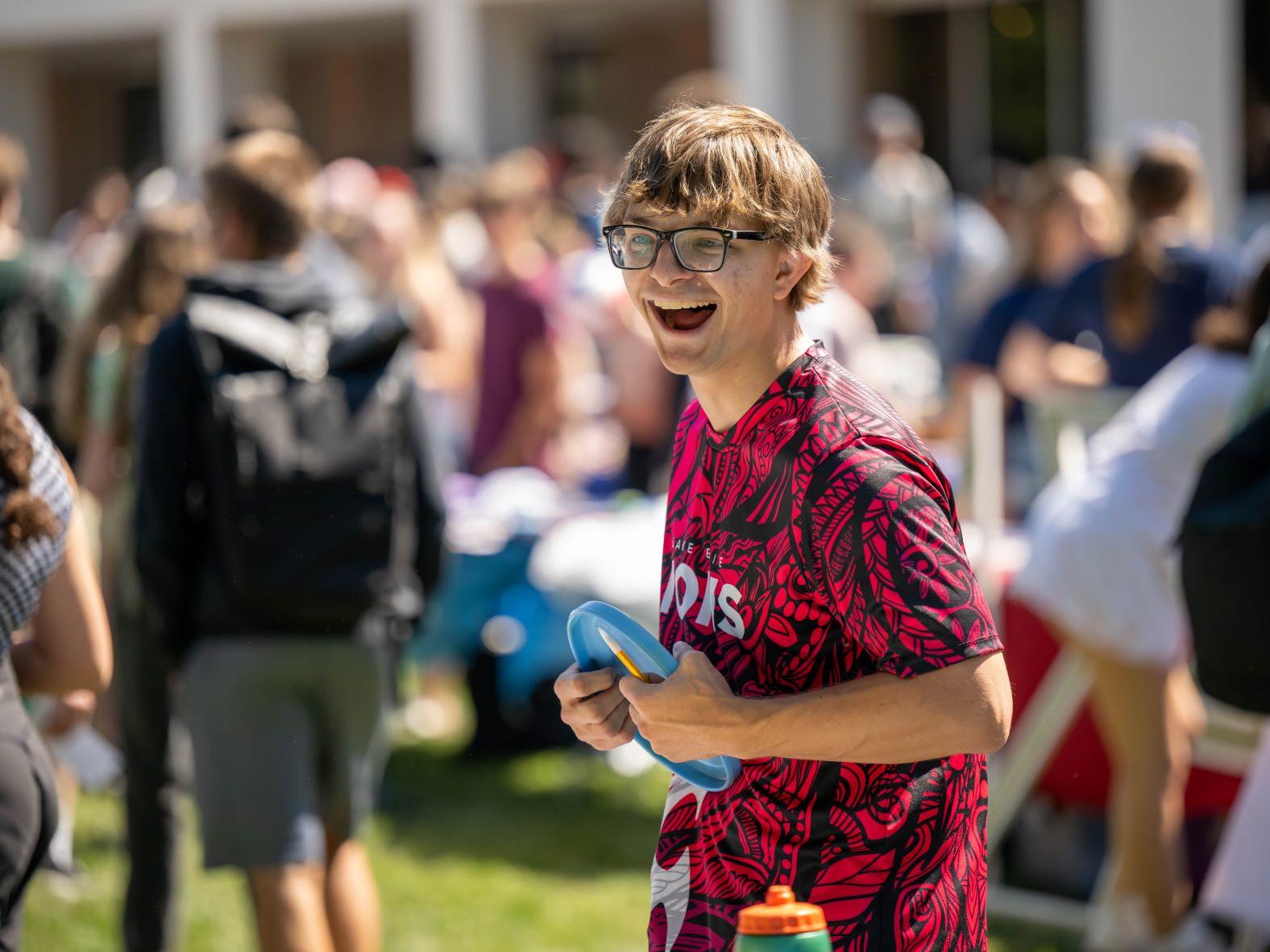 A male student laughs while holding a Frisbee at Penn State Behrend's Discovery Fair.