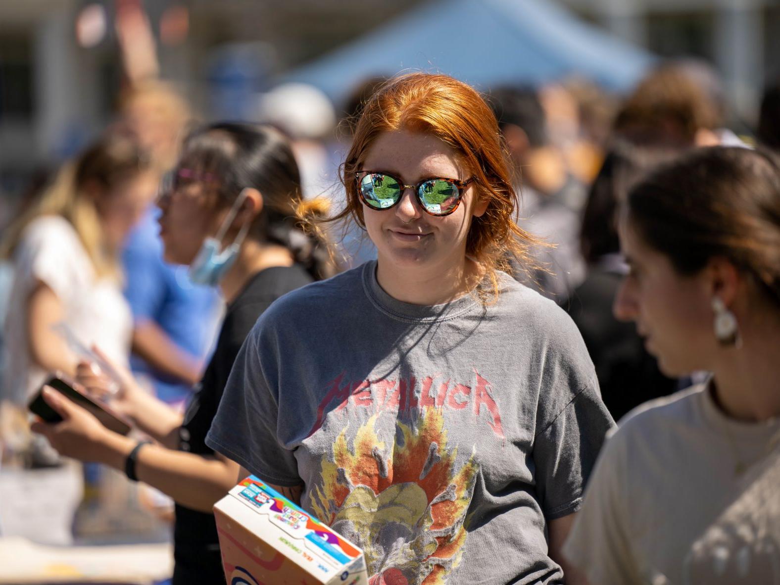 A female student in reflecting sunglasses looks at displays at Penn State Behrend's Discovery Fair.