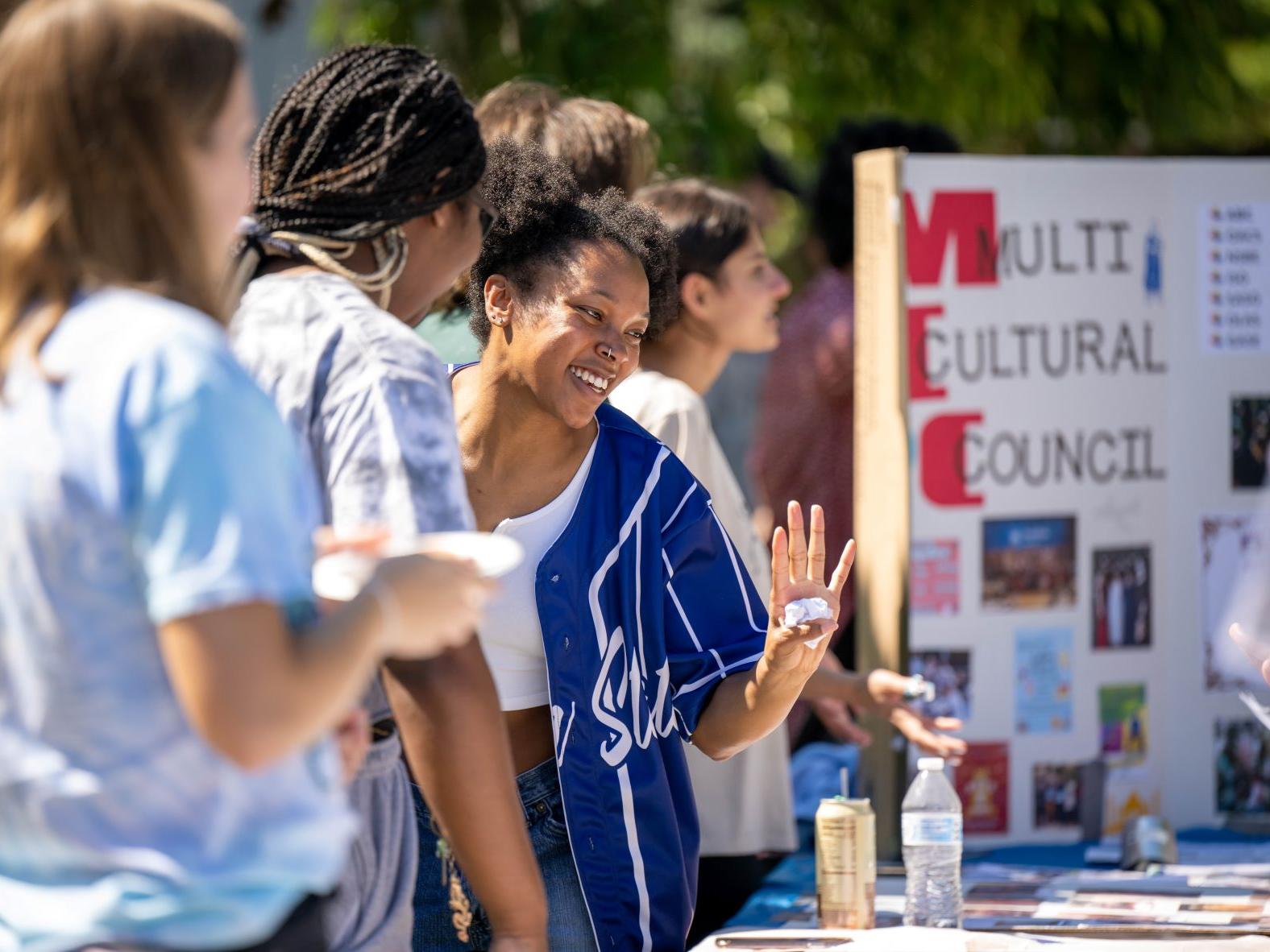 A group of female students laughs while talking at a table at Penn State Behrend's Discovery Fair.