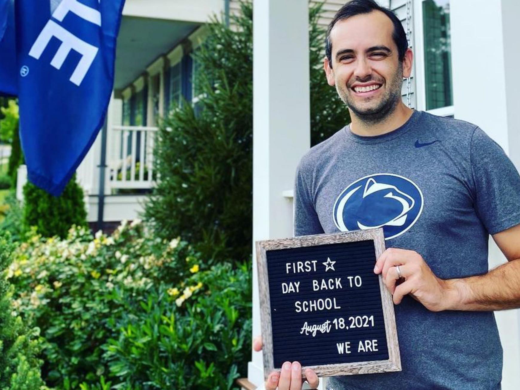 Geoff Calver holds a letterboard that says "First Day Back to school August 18, 2021 We are"