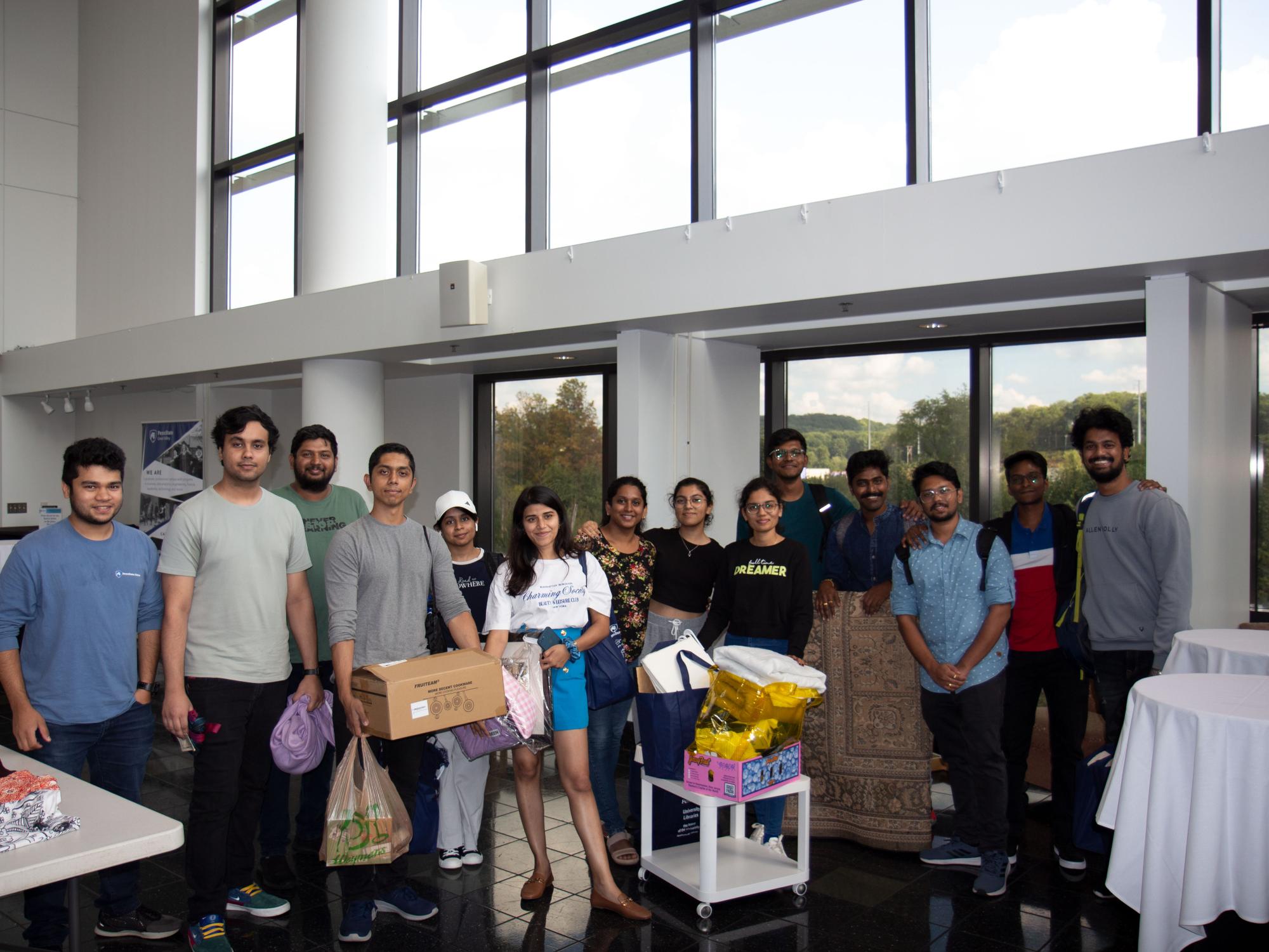 Students holding clothes and household items in the CCB lobby
