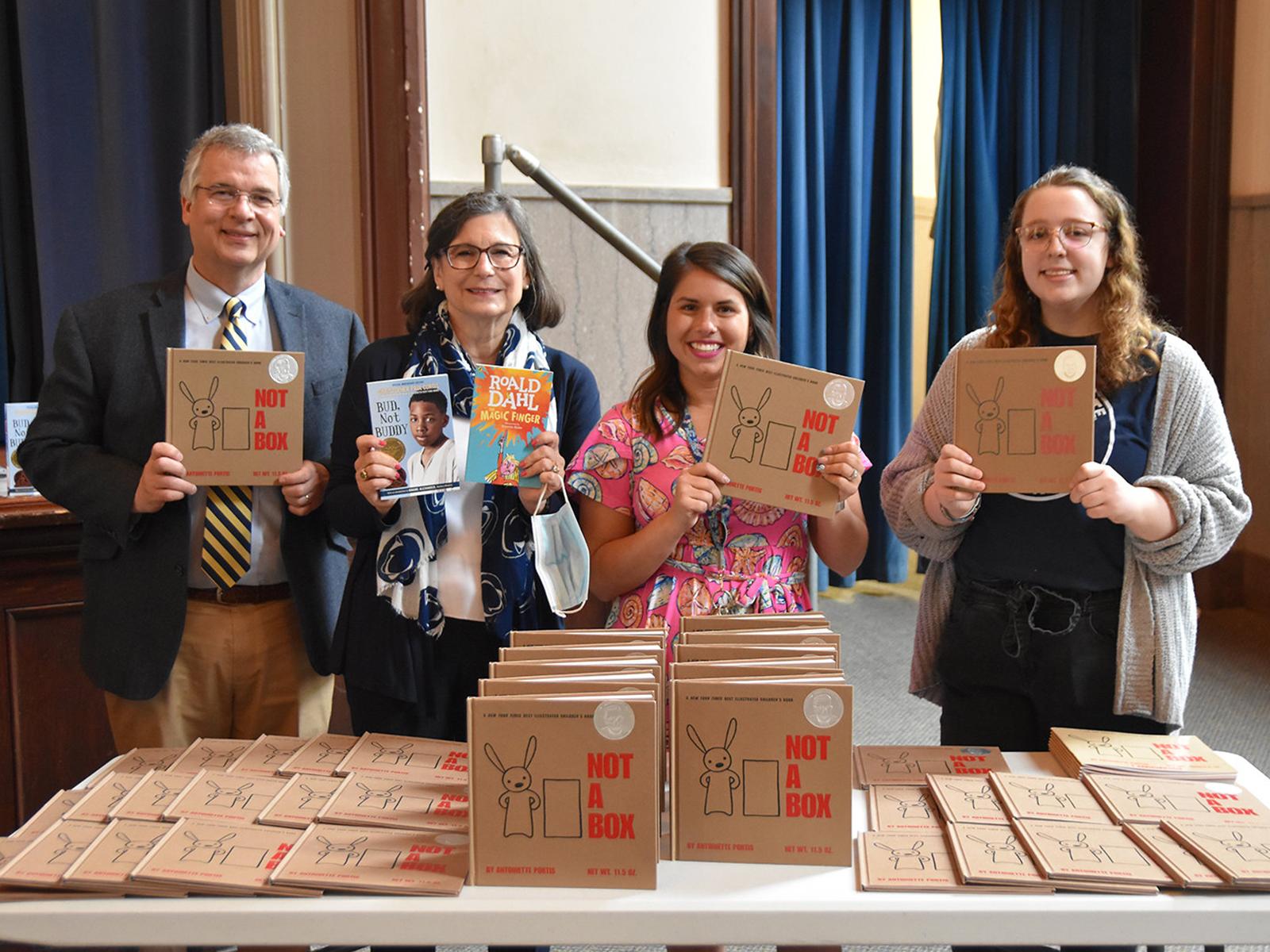 Man wearing glasses and three females holding copies of book.