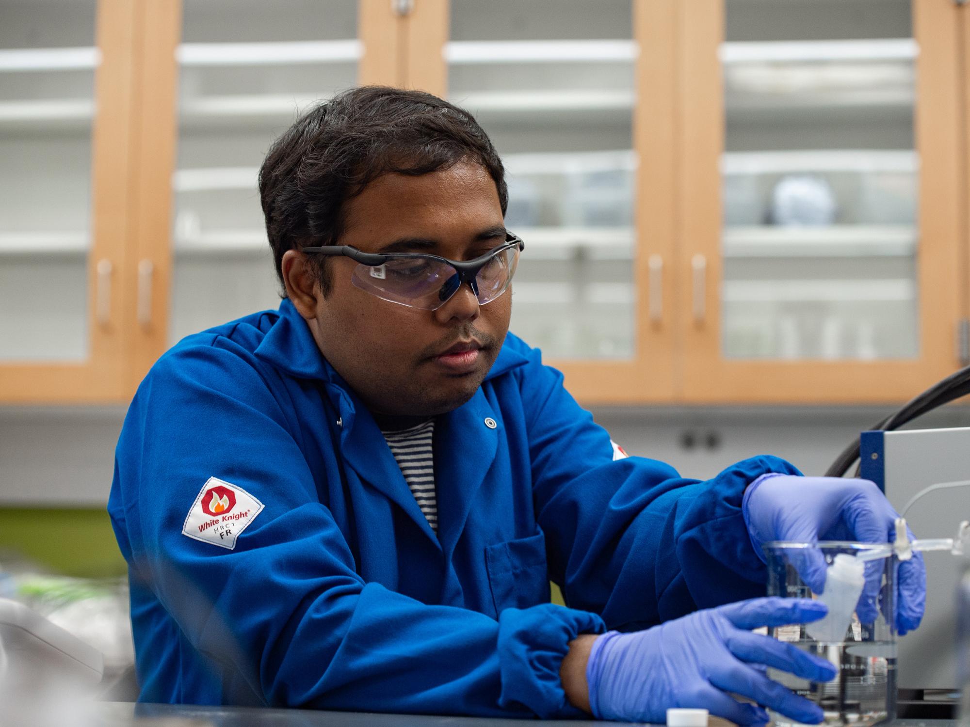 A researcher manipulates laboratory water purification instruments in a lab.