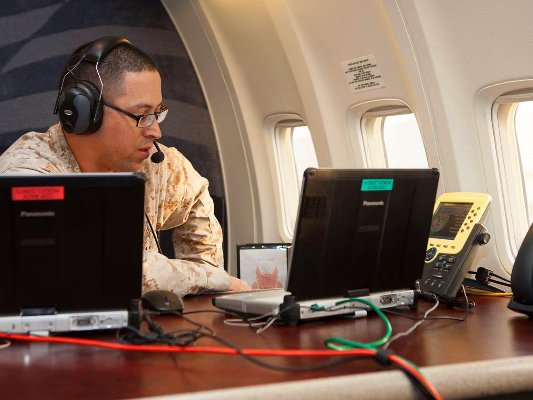 Roberto Rodriguez on board a plane working with two laptops and two phone sets.