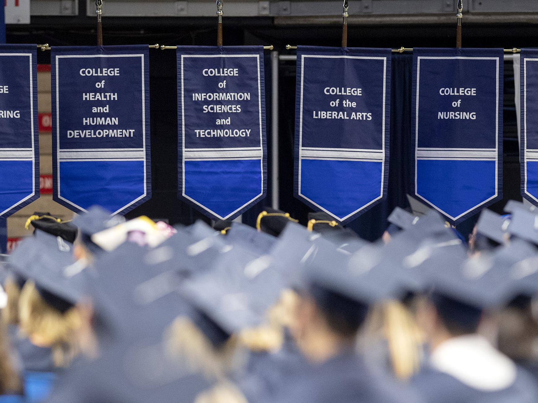 Banners from the colleges of Engineering, Health and Human Development, Information Sciences and Technology, Liberal Arts, Nursing and Science hang during commencement.