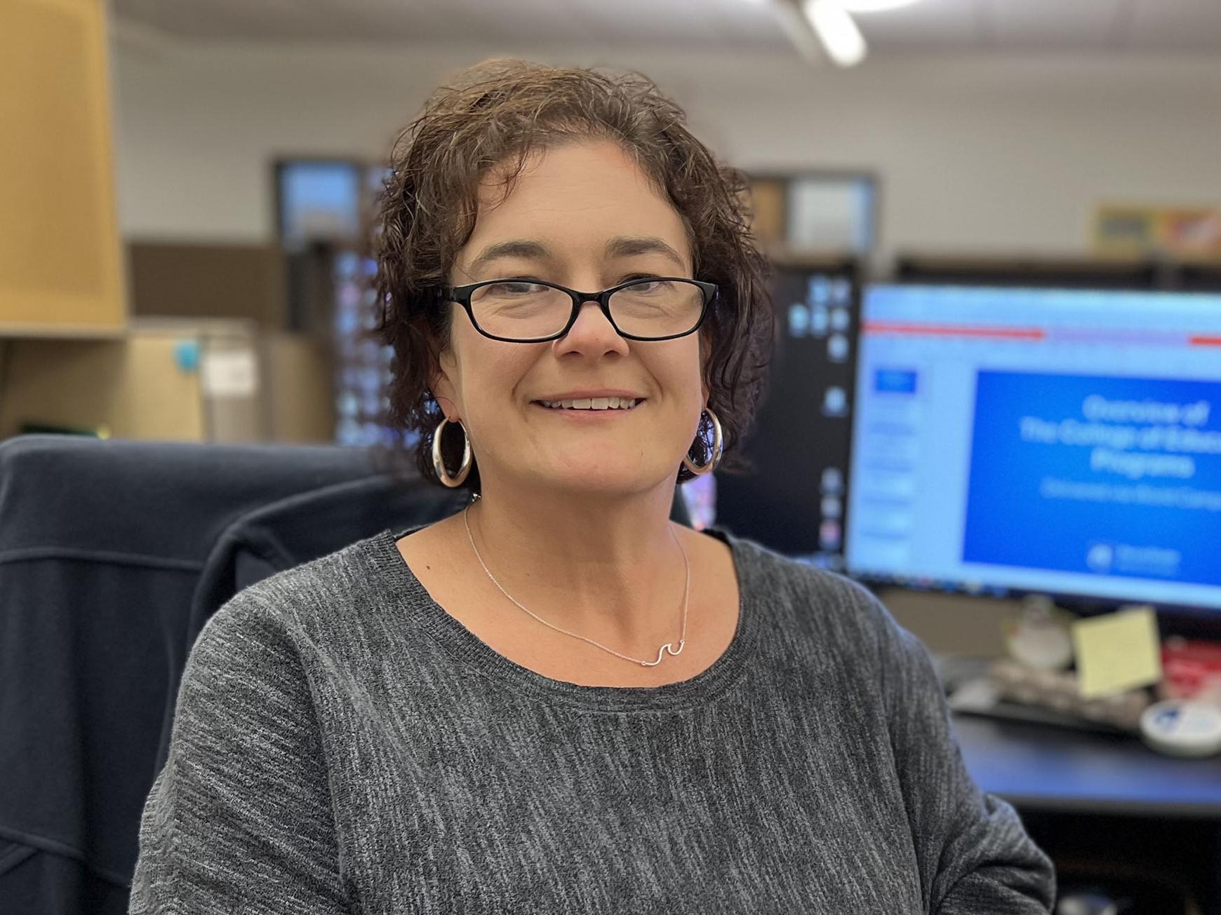 Tracey McCloskey sits at her cubicle in the Outreach Building