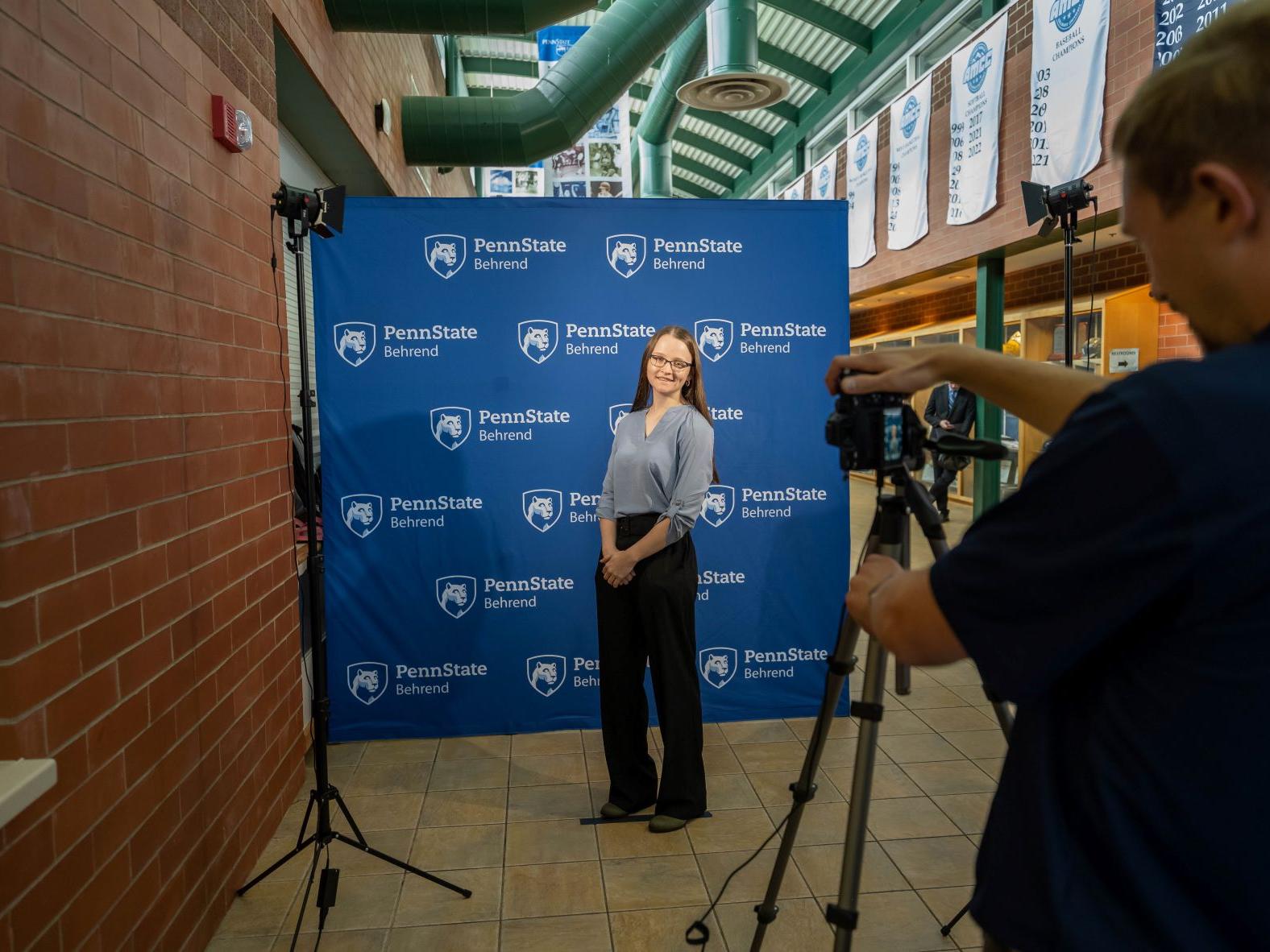 A student photographs another student in front of a professional backdrop at Penn State Behrend's fall career fair.