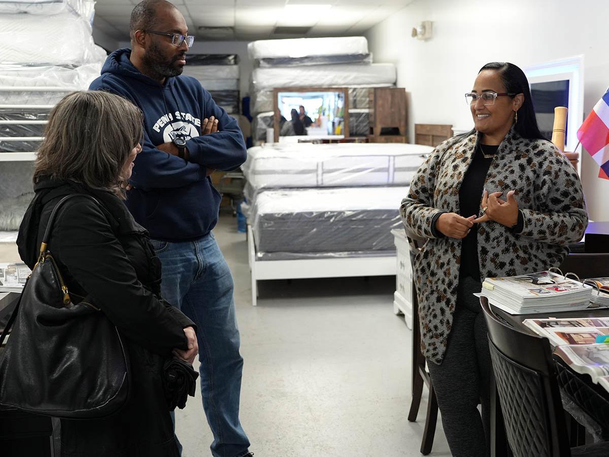 Business owner speaking with male and female Penn State Hazleton employees inside business.
