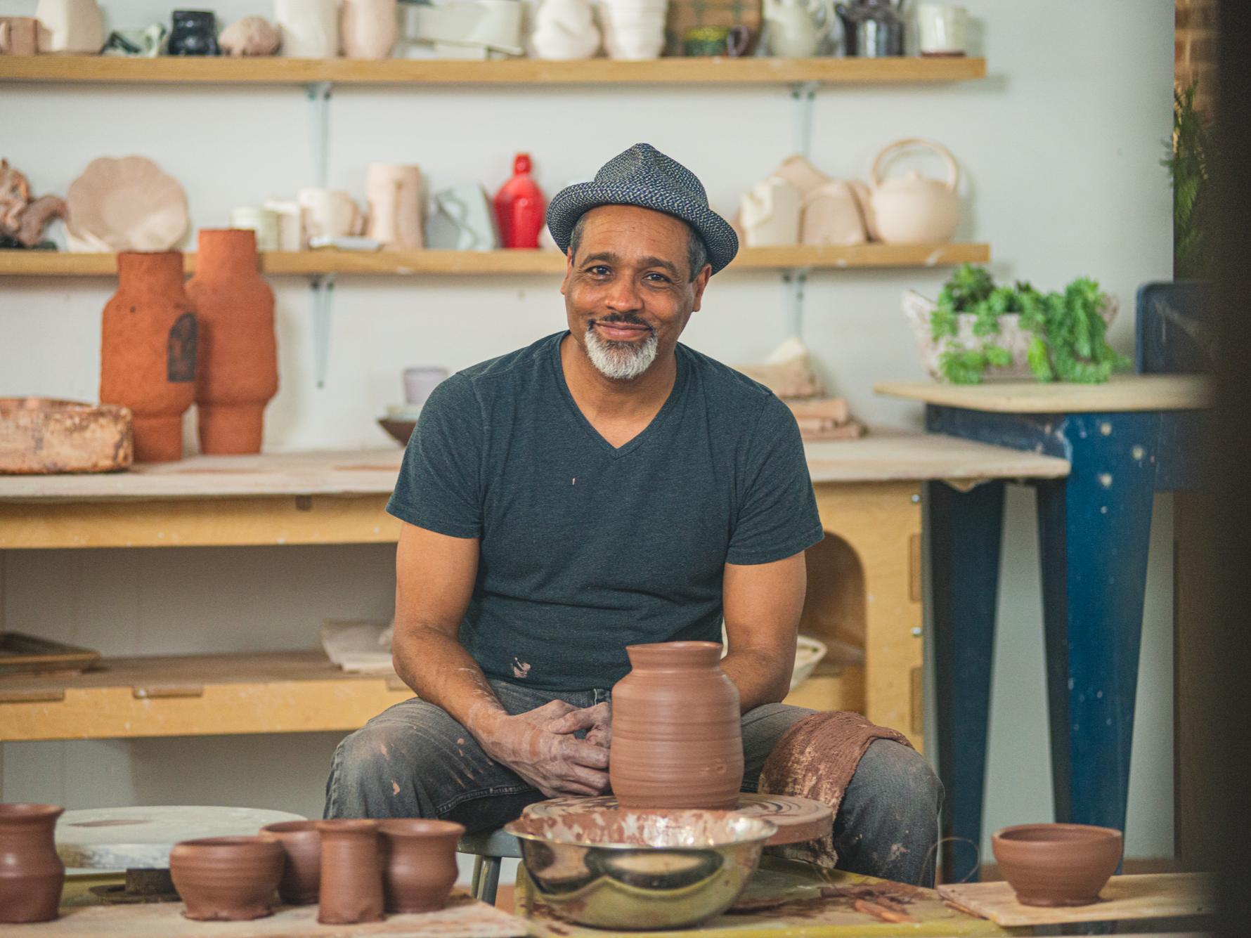  B Stephen Carpenter II sits with a satisfied smiled behind a freshly molded clay urn