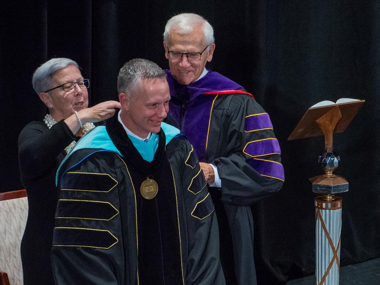 David Jane Gilmour and state Sen. Gene Yaw place the Penn College Presidential Medallion around the neck of new Penn College President Michael J. Reed.