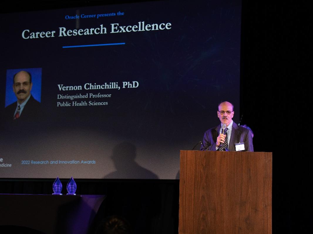 Vernon Chinchilli stands at a podium to speak during the Research and Innovation Awards Ceremony. 