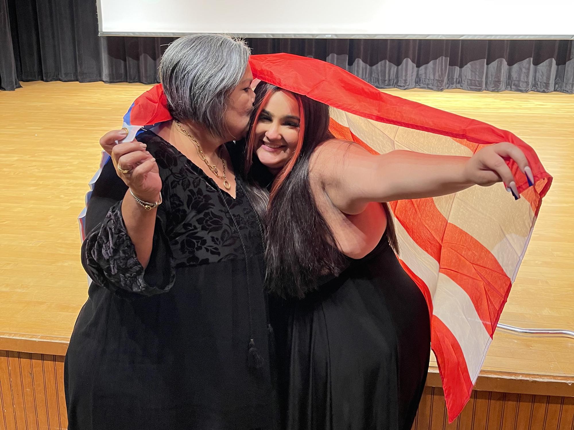 Zairi Mercader with her grandmother at Noche Latina, both holding the Puerto Rican flag.