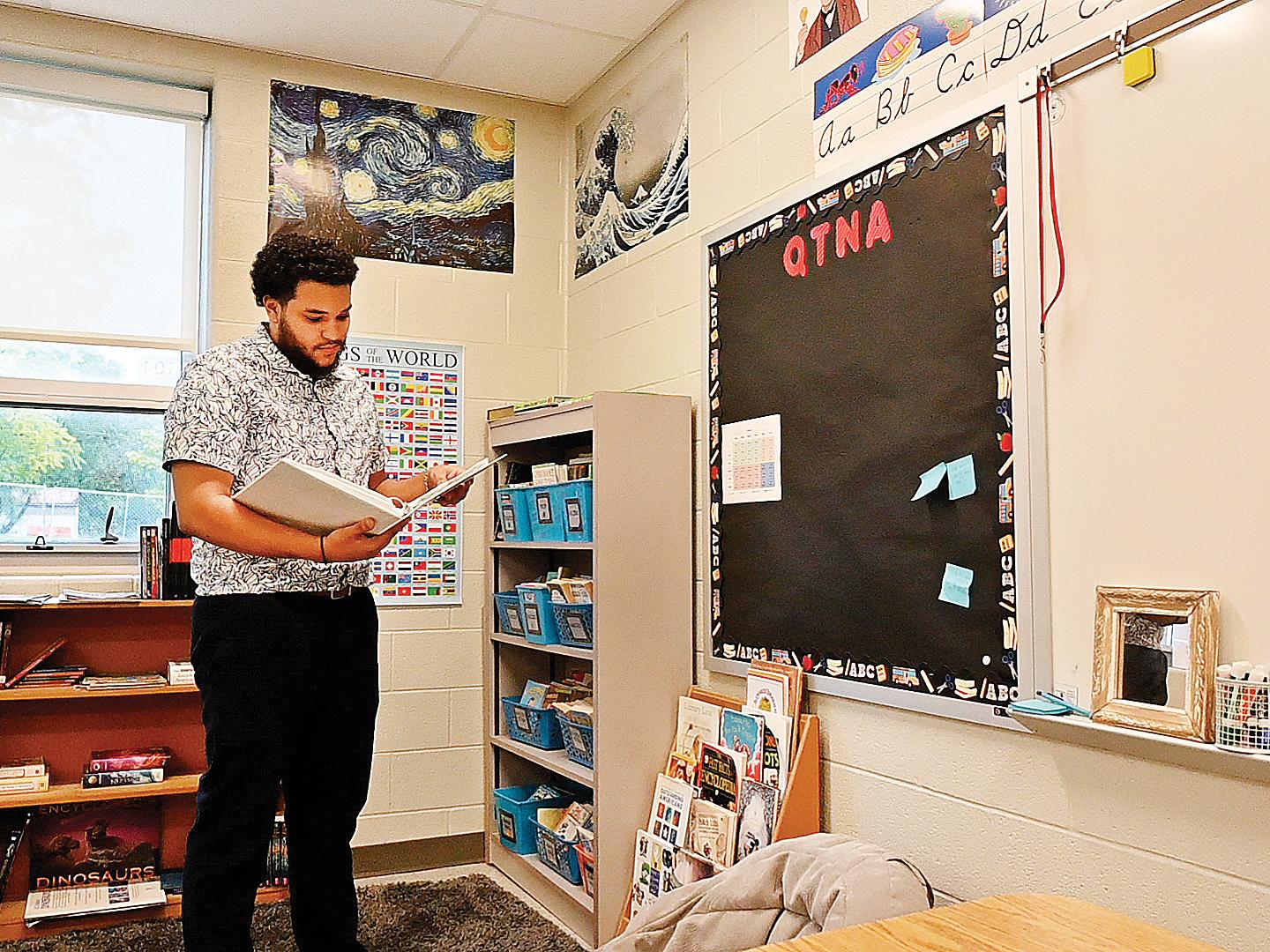 Brandon Reed-Porter looks at a book inside his classroom.