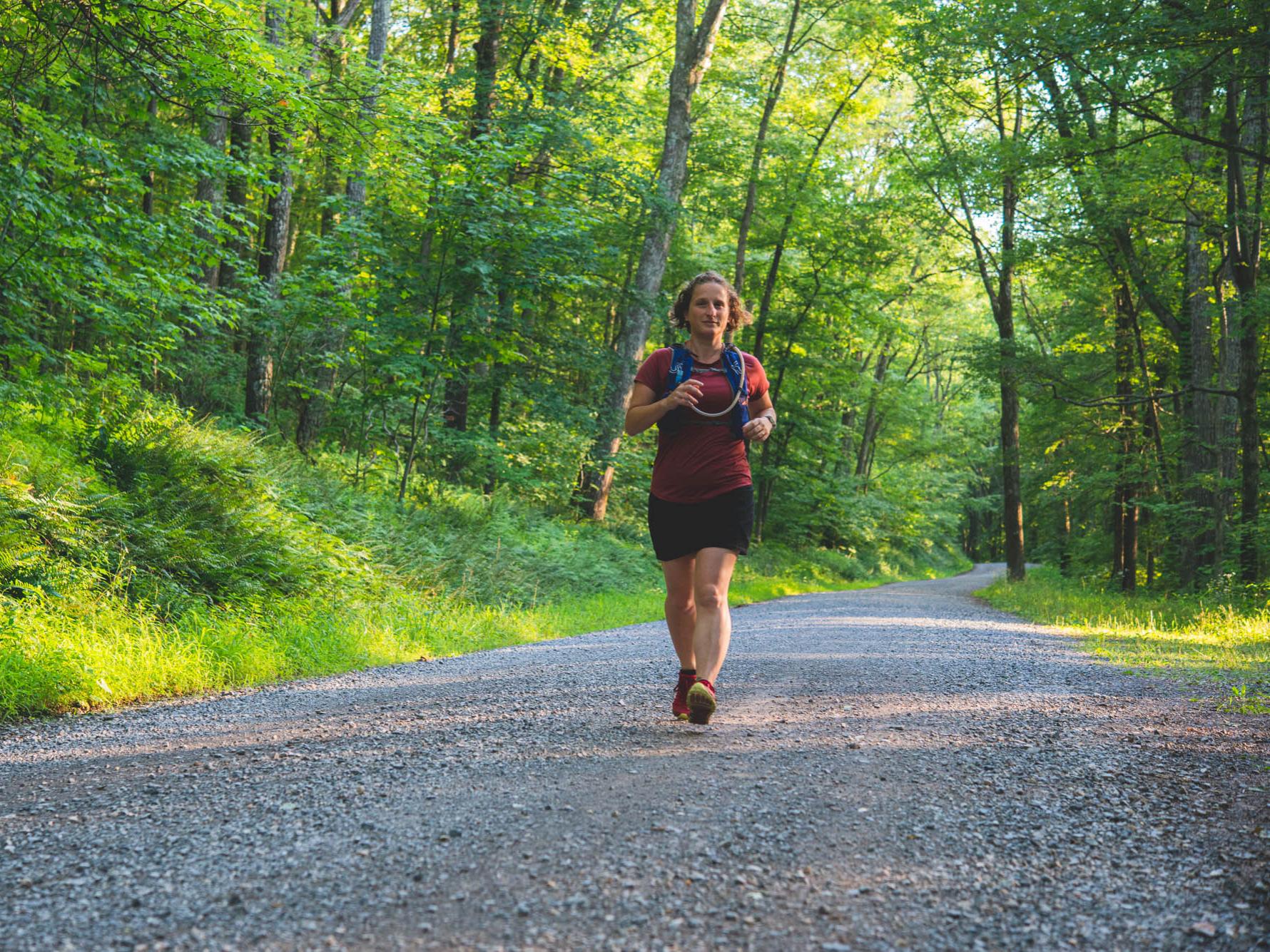 Tracy Langkilde, dean of the Eberly College of Science and a dedicated trail runner, runs down a gravel road surrounded by greenery