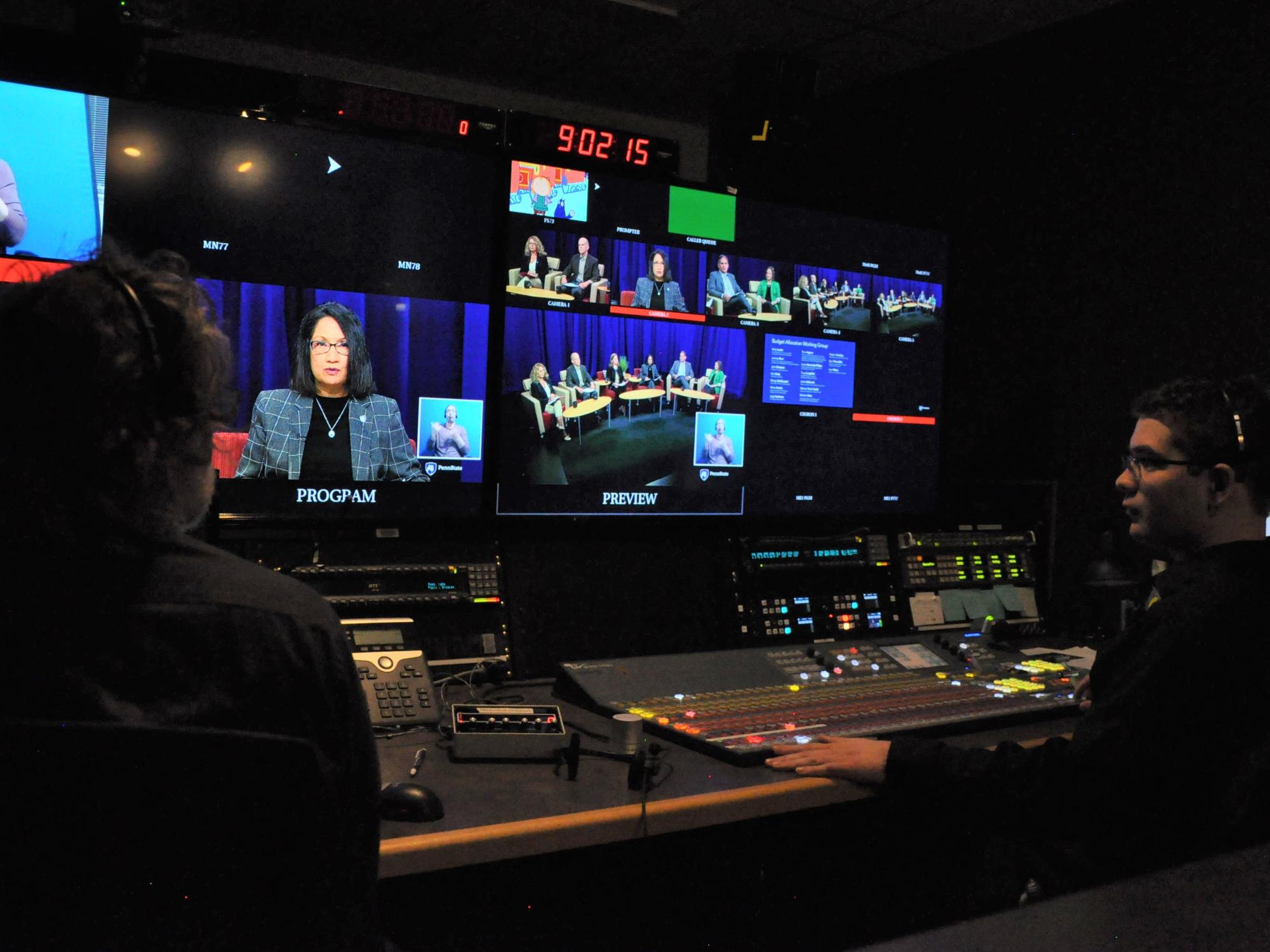 Two members of WPSU's staff run the livestream from a control room in front of a series of screens