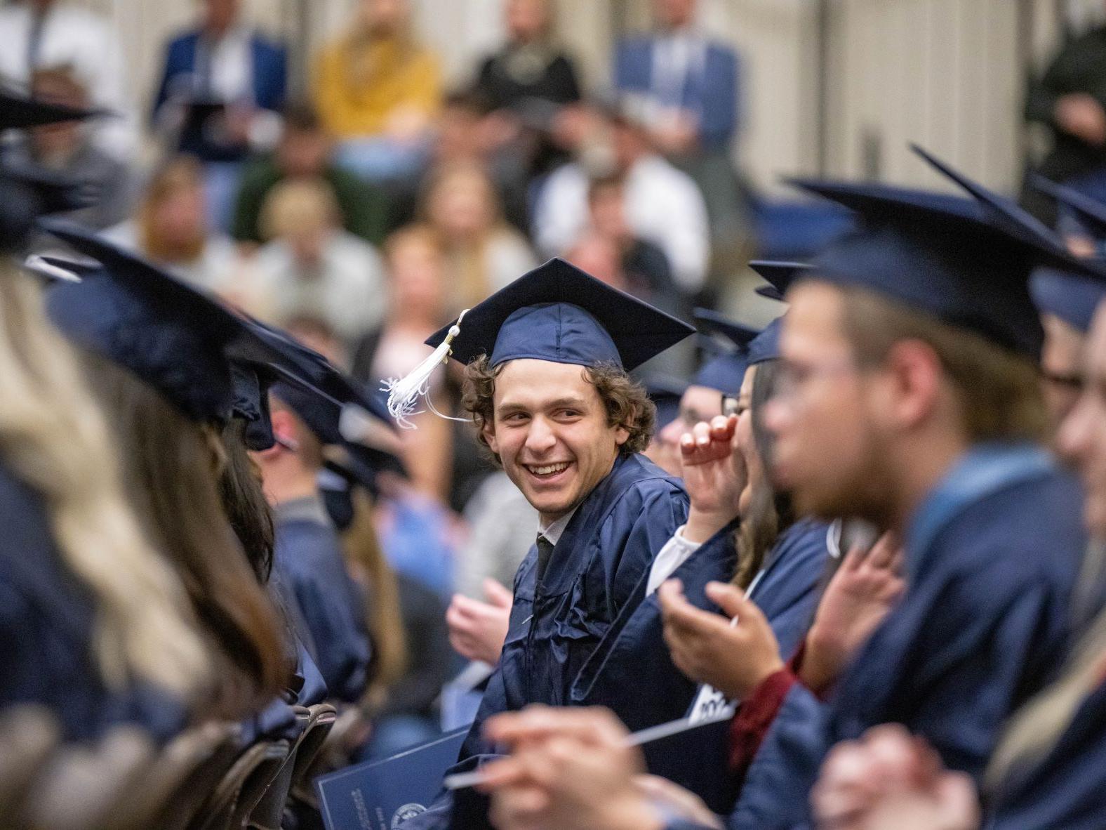 A new graduate turns to look at a classmate during Penn State Behrend's fall 2022 commencement program.