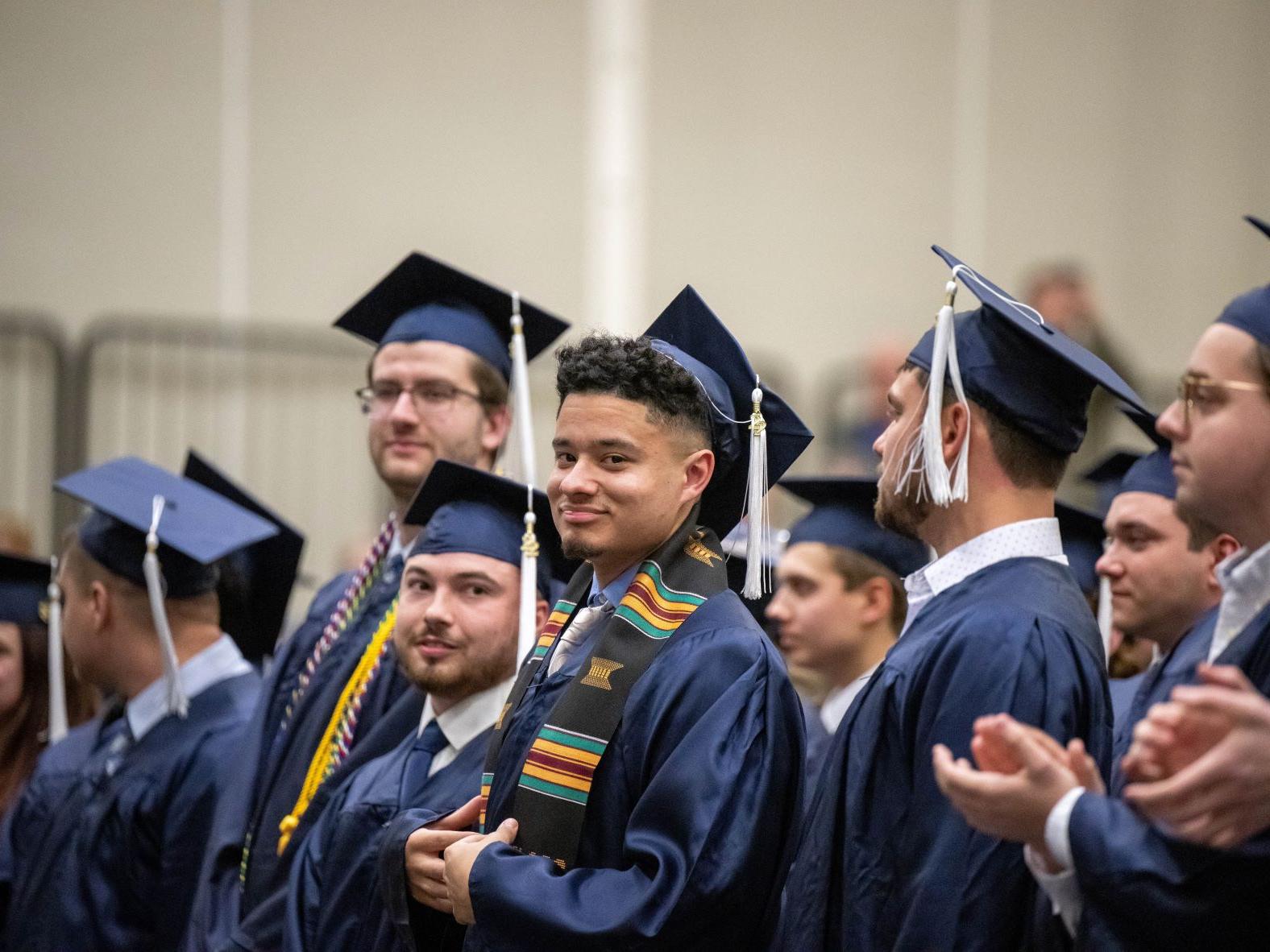 New graduates smile and applaud during Penn State Behrend's fall 2022 commencement program.