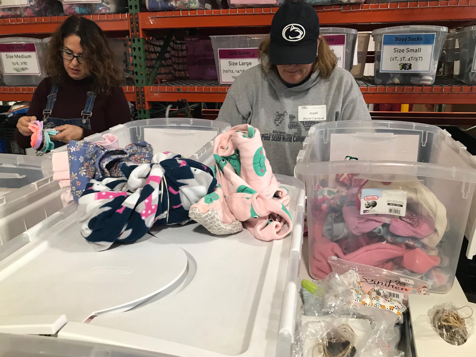 Two people sort clothes in a warehouse.