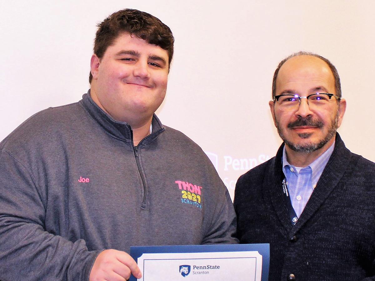 smiling chancellor presents smiling student with certificate