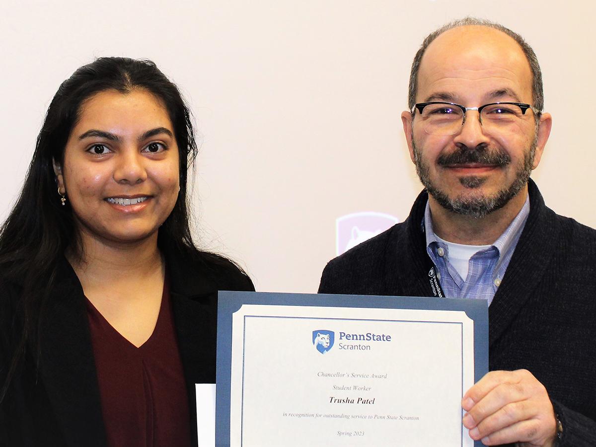 smiling chancellor presents smiling student with certificate