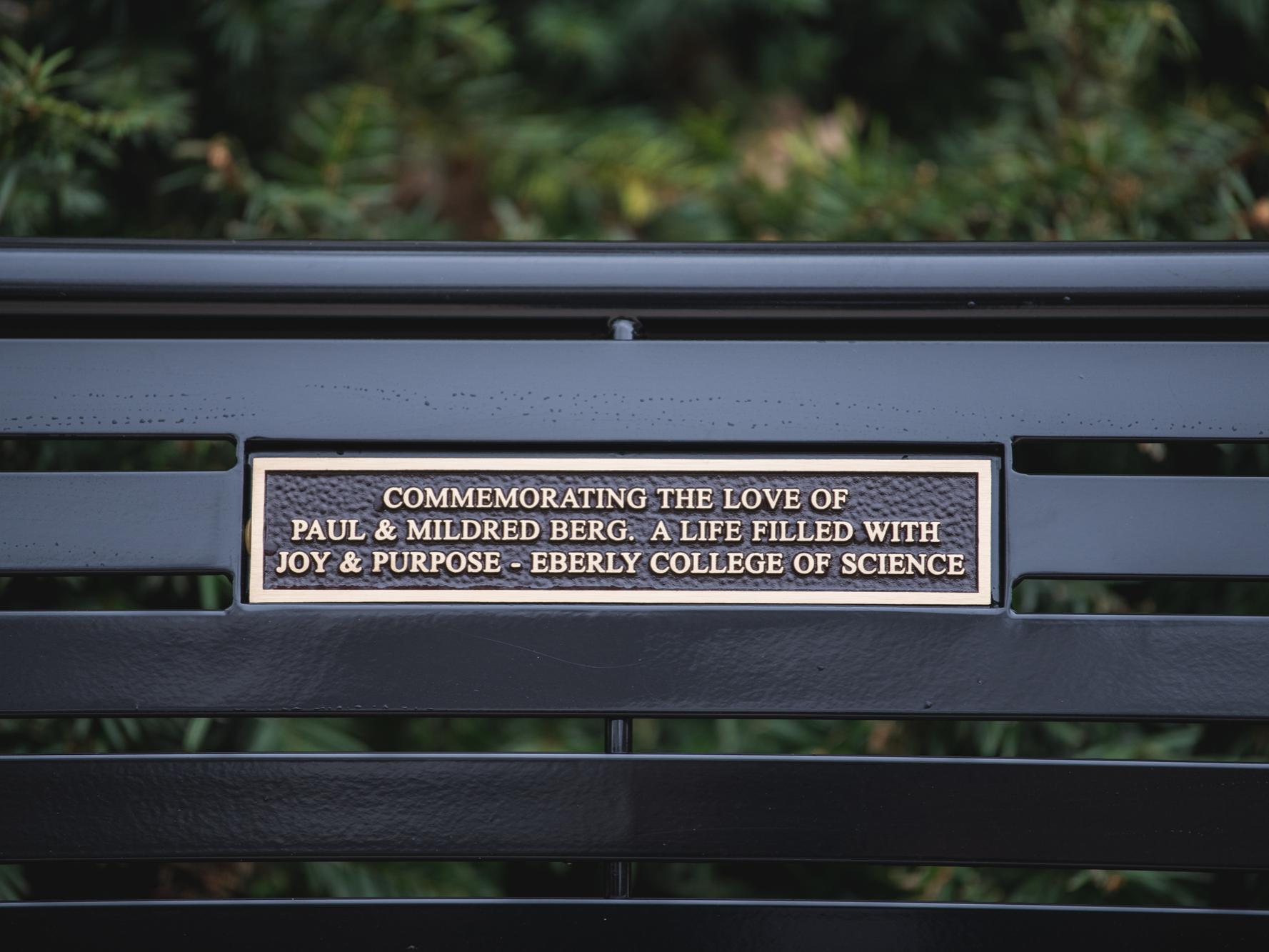Bench commemorating Paul and Mildred Berg, with a plaque that reads Commemorating the love of Paul & Mildred Berg. A life filled with joy & purpose -- Eberly College of Science
