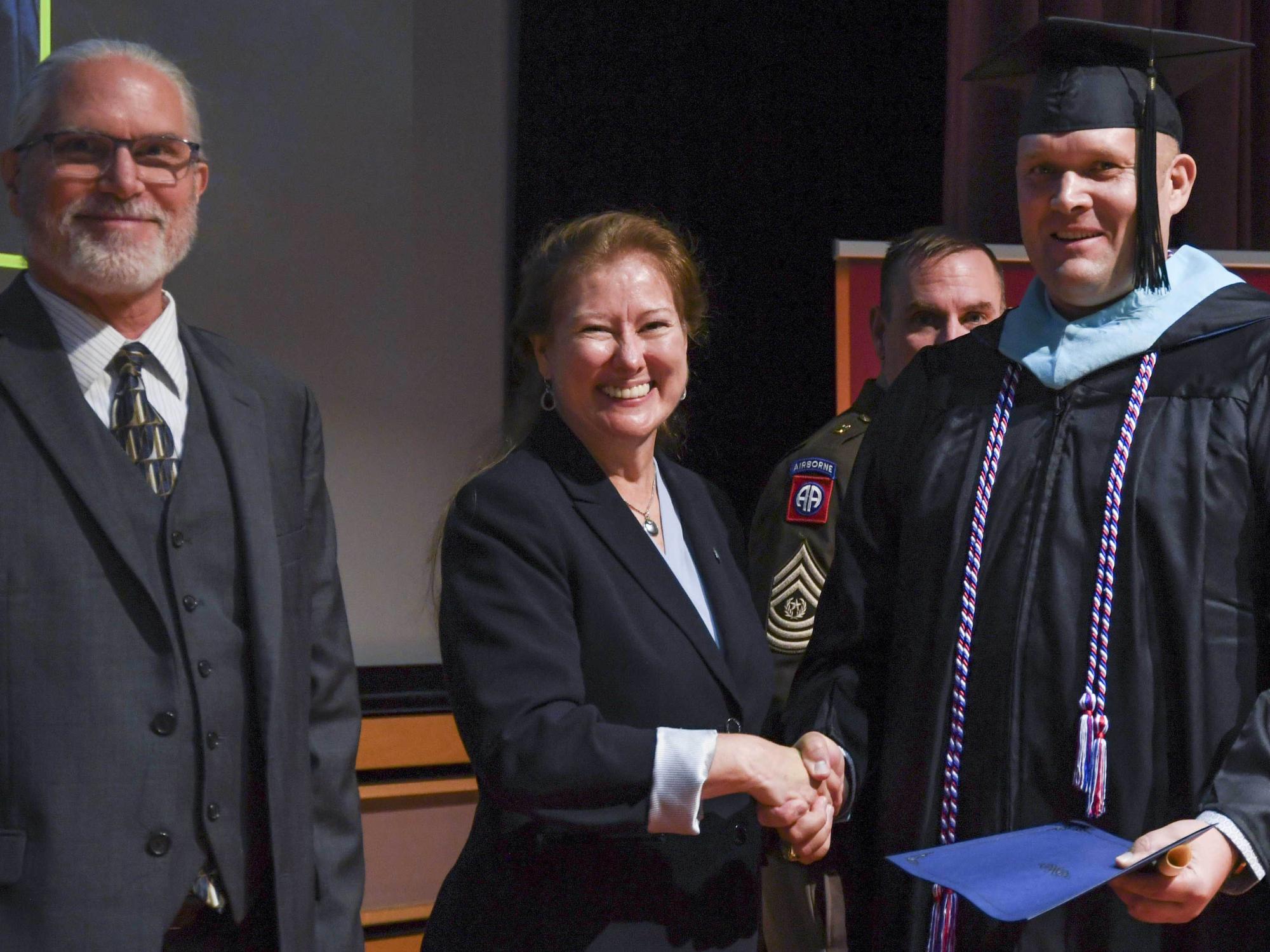 Aaron Beckman shakes hands with Renata Engel while Will Diehl stands to the left