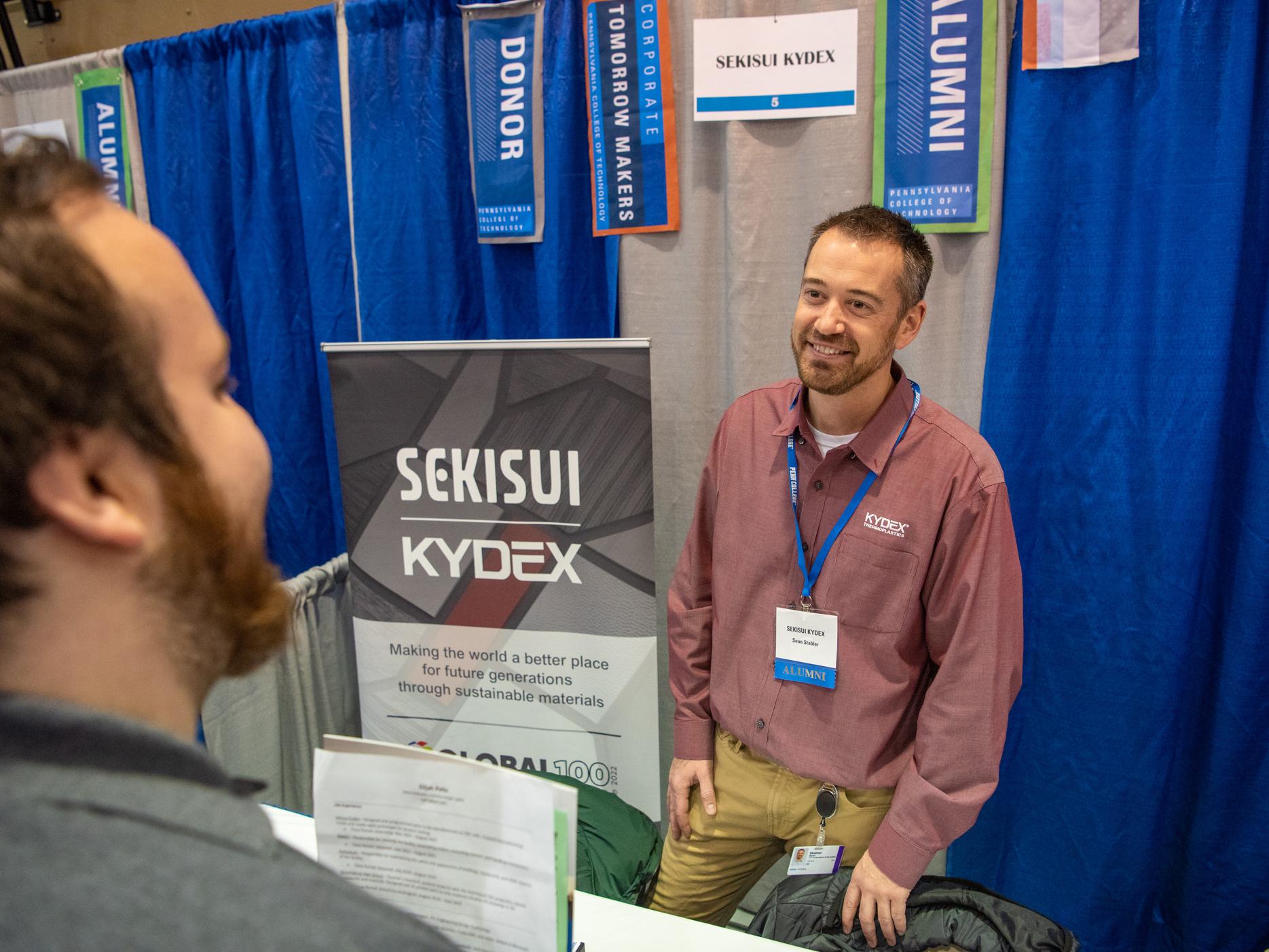 An employer and alum of Penn College speaks to a student at the career fair.