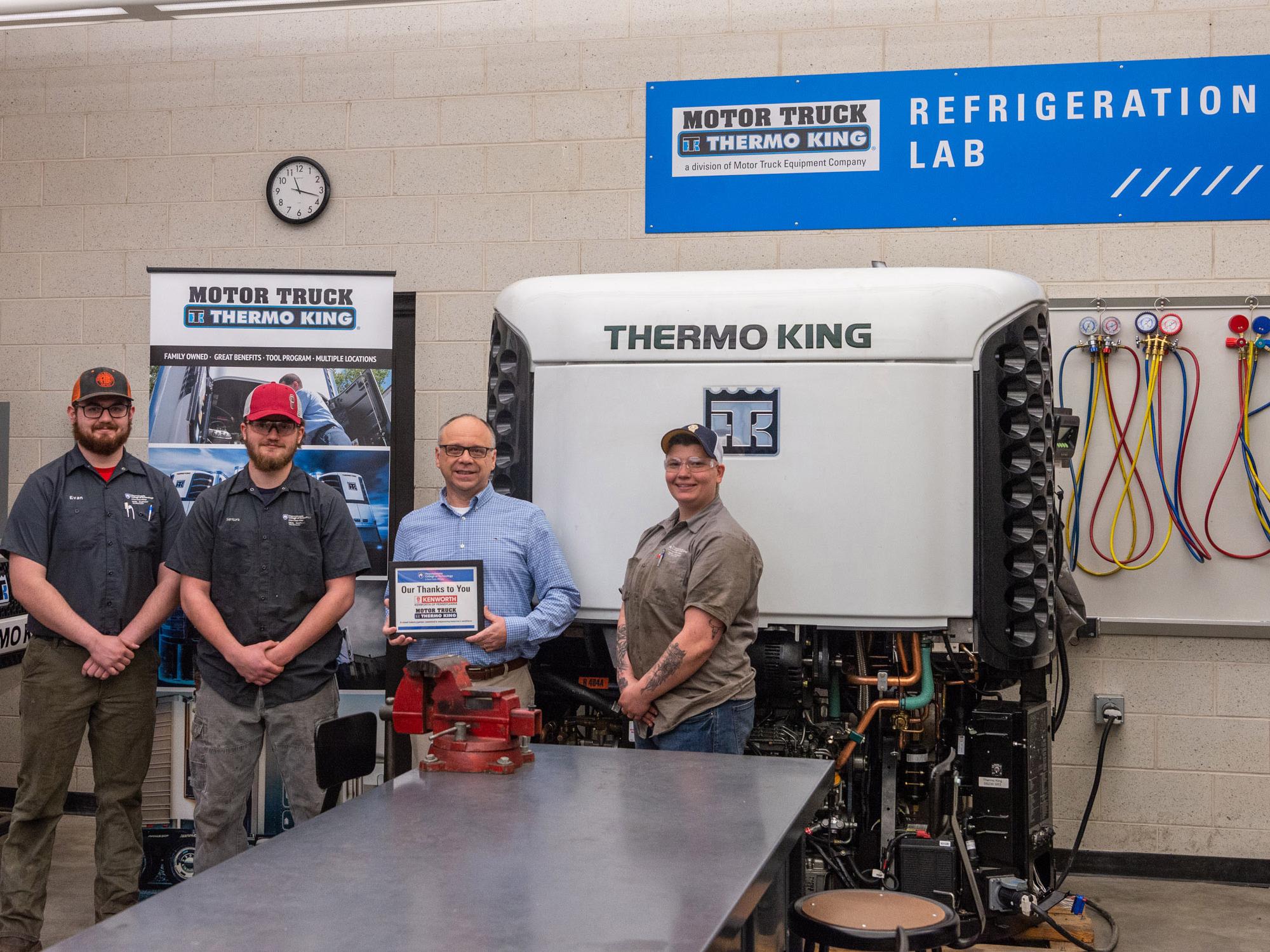 Four people pose for a photograph in a lab with equipment