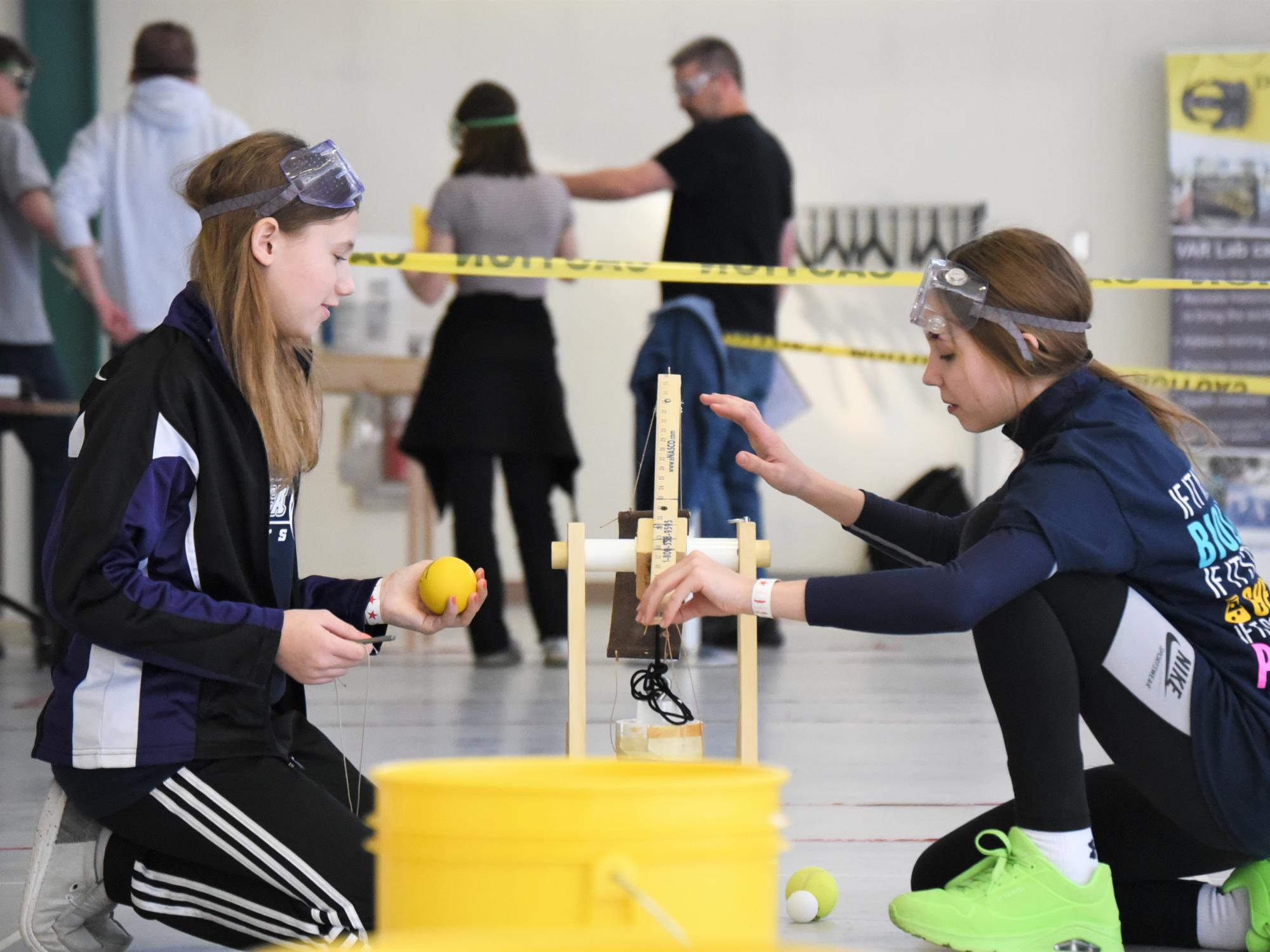 Two girls adjust a model trebuchet at the regional Science Olympiad at Penn State Behrend.