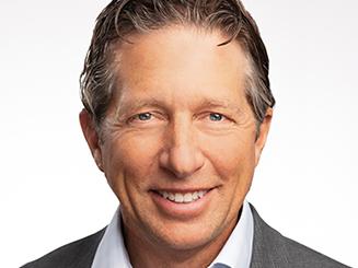 Smiling man with blue shirt and gray coat