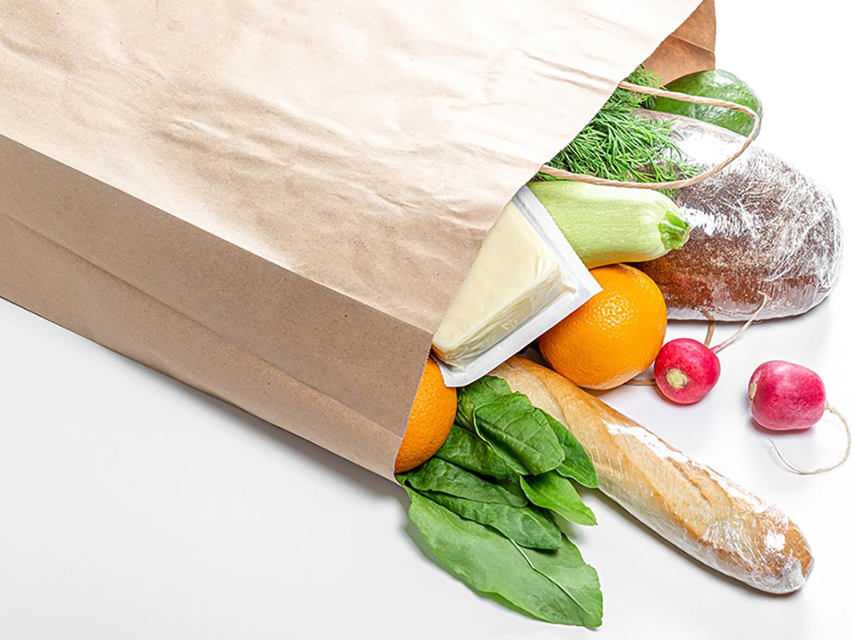 A photo of a brown paper bag with groceries spilling out of it