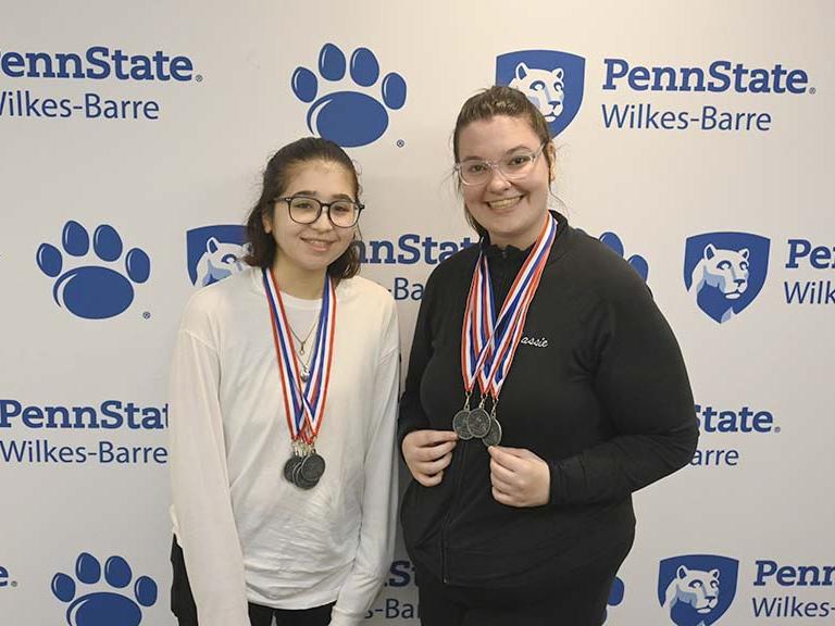 Two winners displaying their award medals